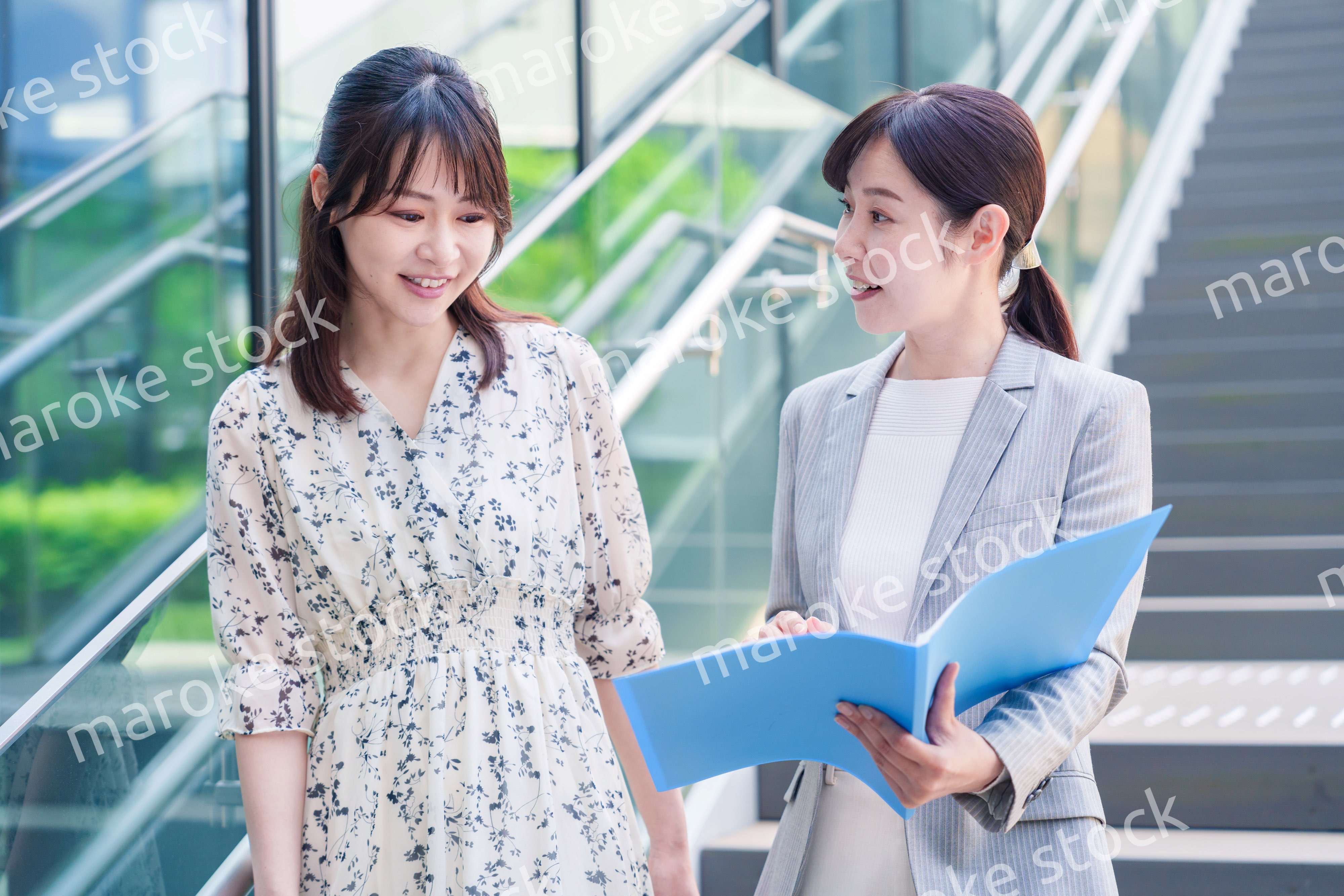 楽しく話しながらオフィスの中を歩く女性ビジネスパーソン