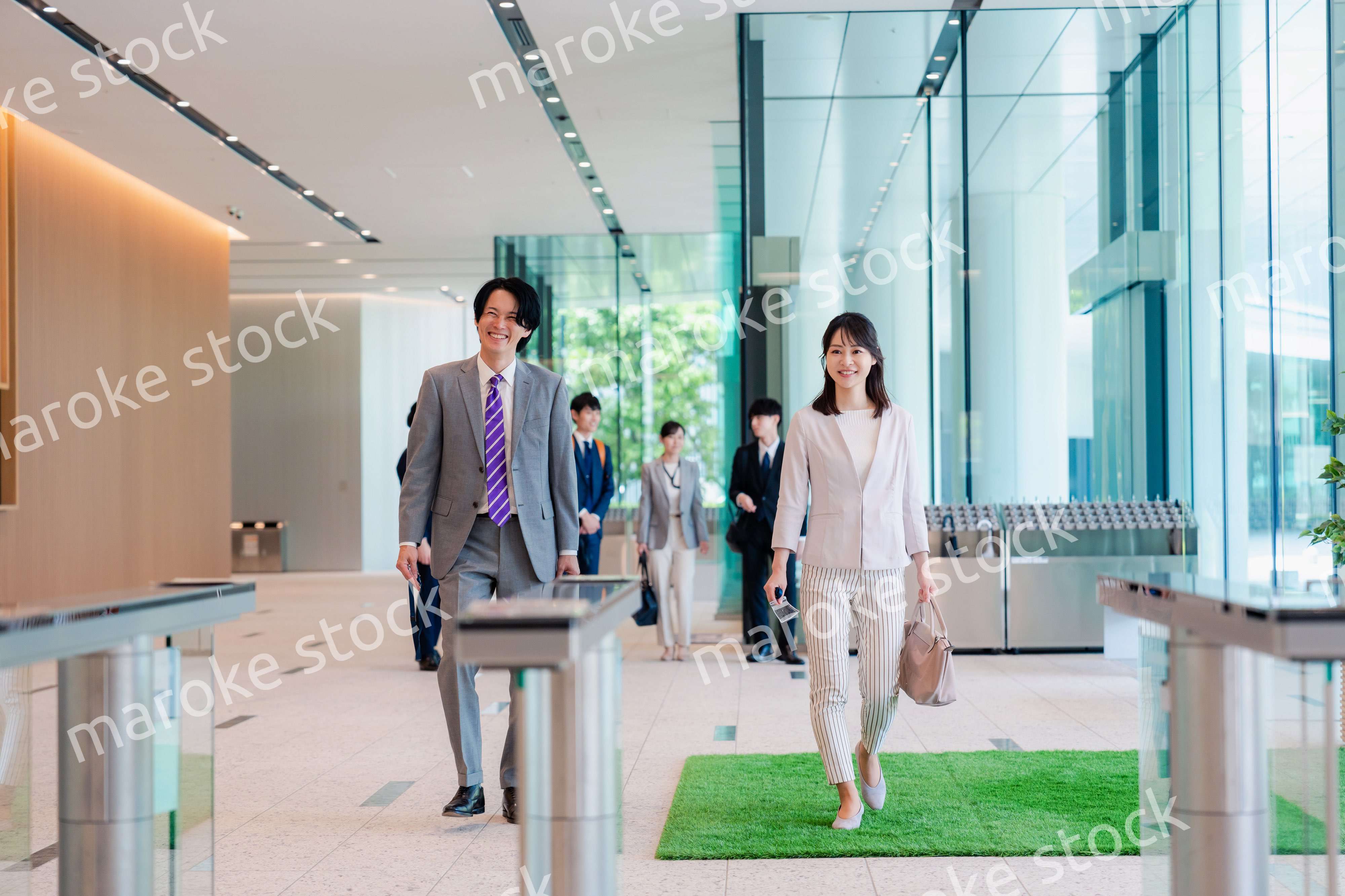 オフィスのエントランスを通るビジネスパーソン