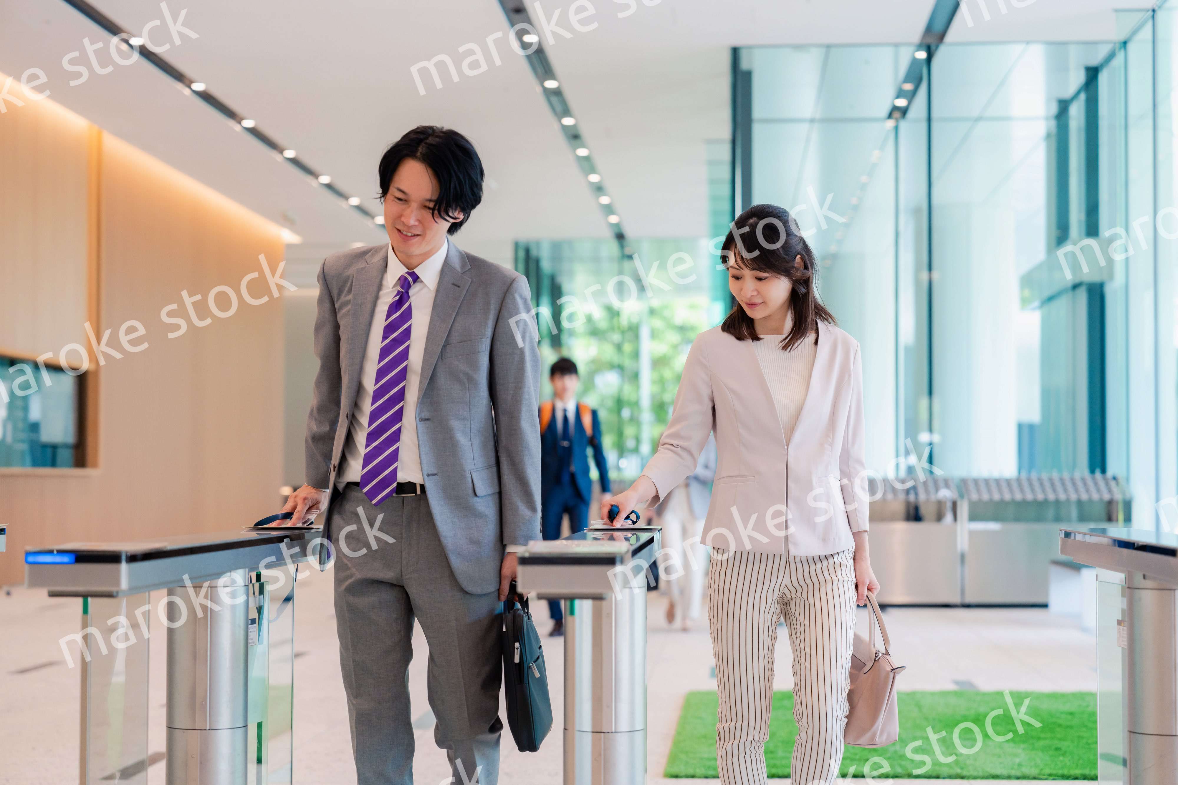 オフィスのエントランスを通るビジネスパーソン