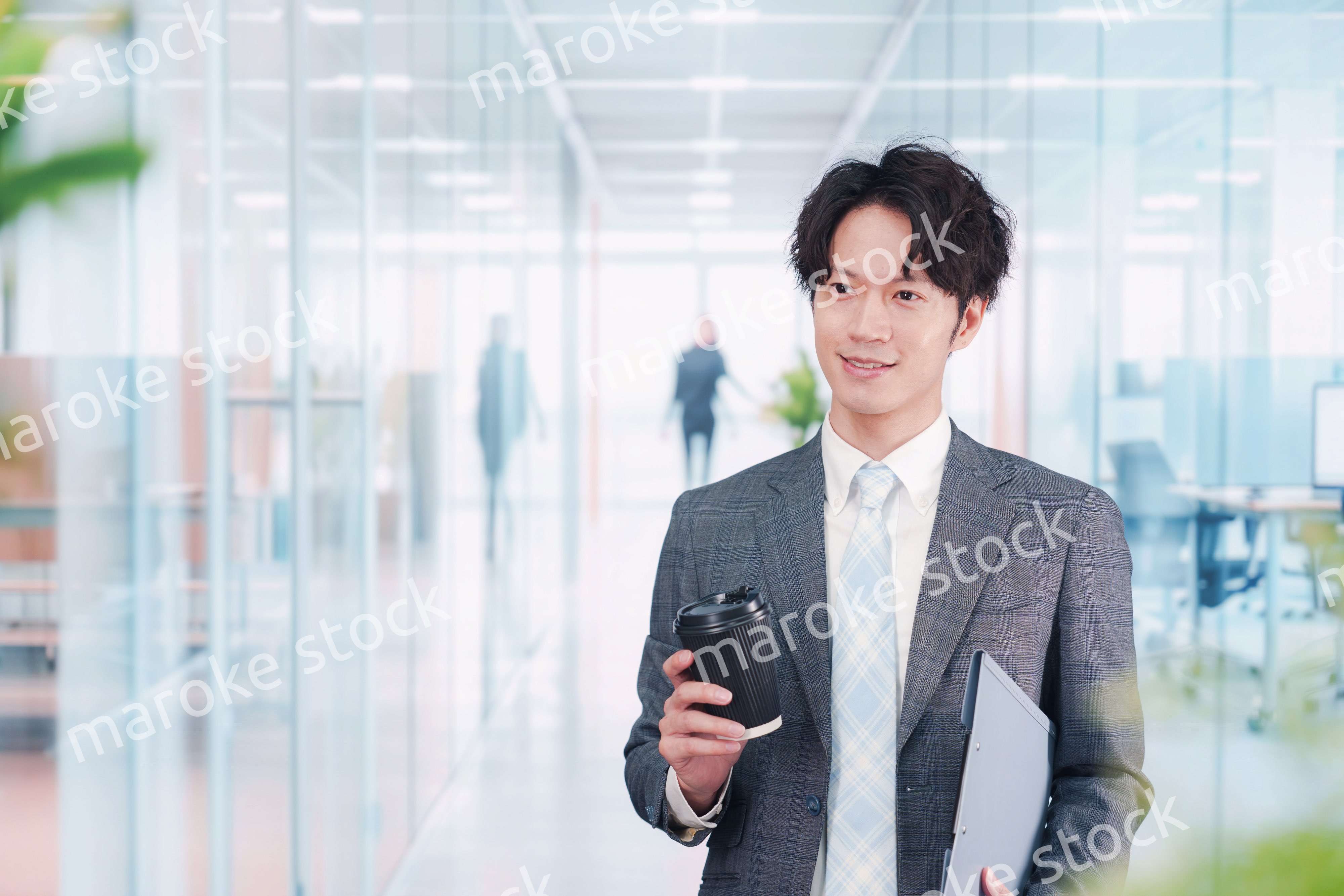 オフィスで紙カップのコーヒーを持って歩くビジネスマン