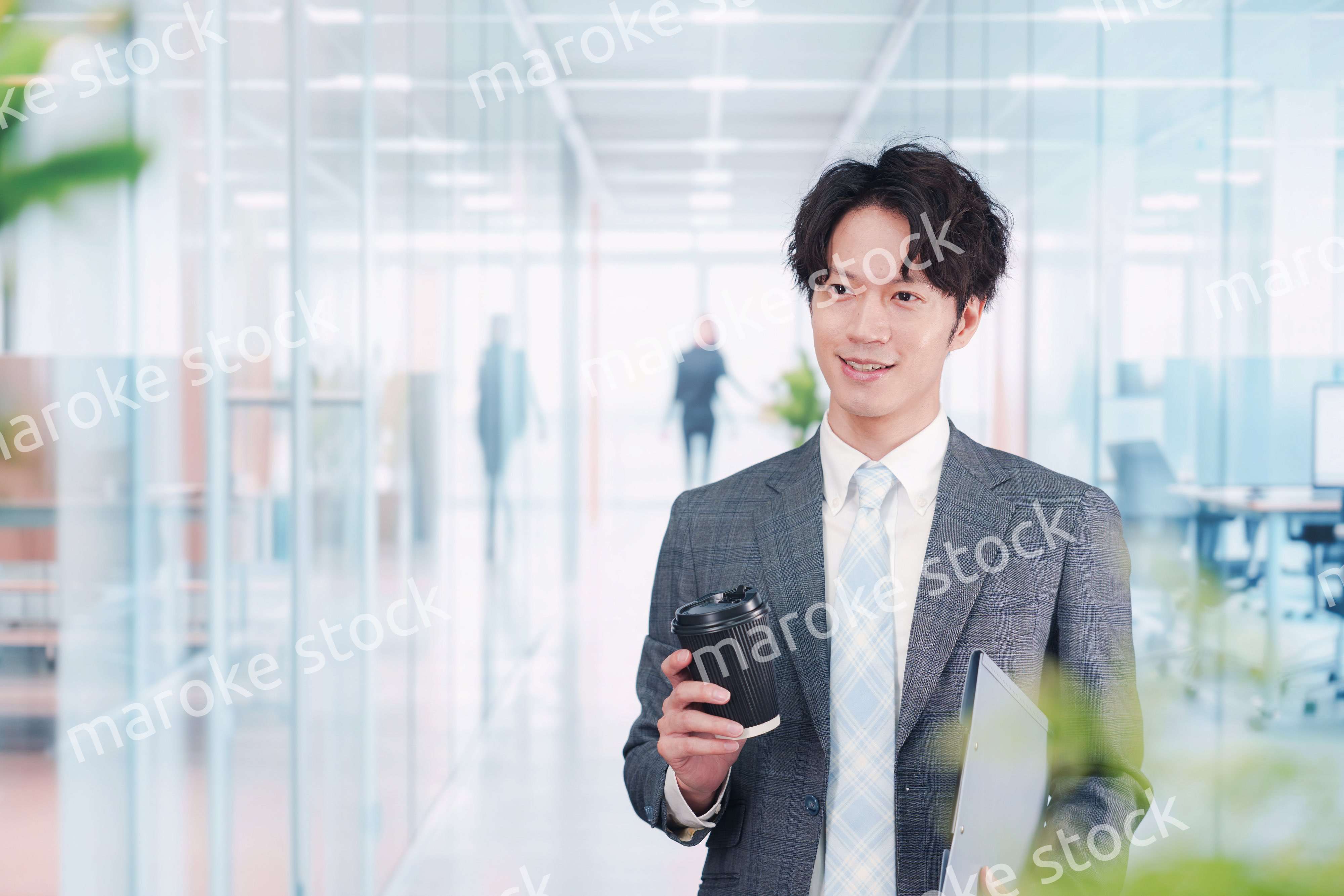 オフィスで紙カップのコーヒーを持って歩くビジネスマン