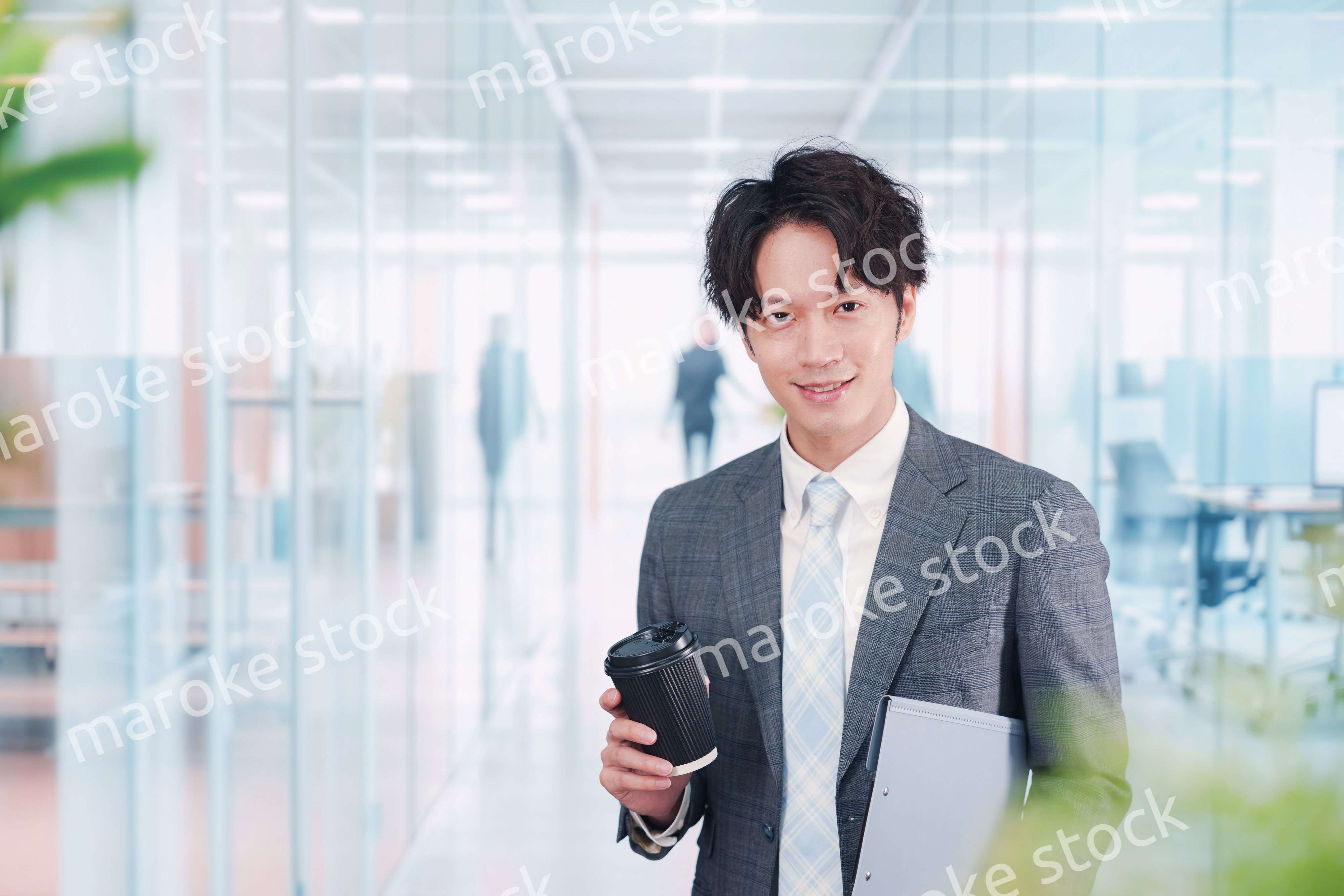 オフィスで紙カップのコーヒーを持って歩くビジネスマン