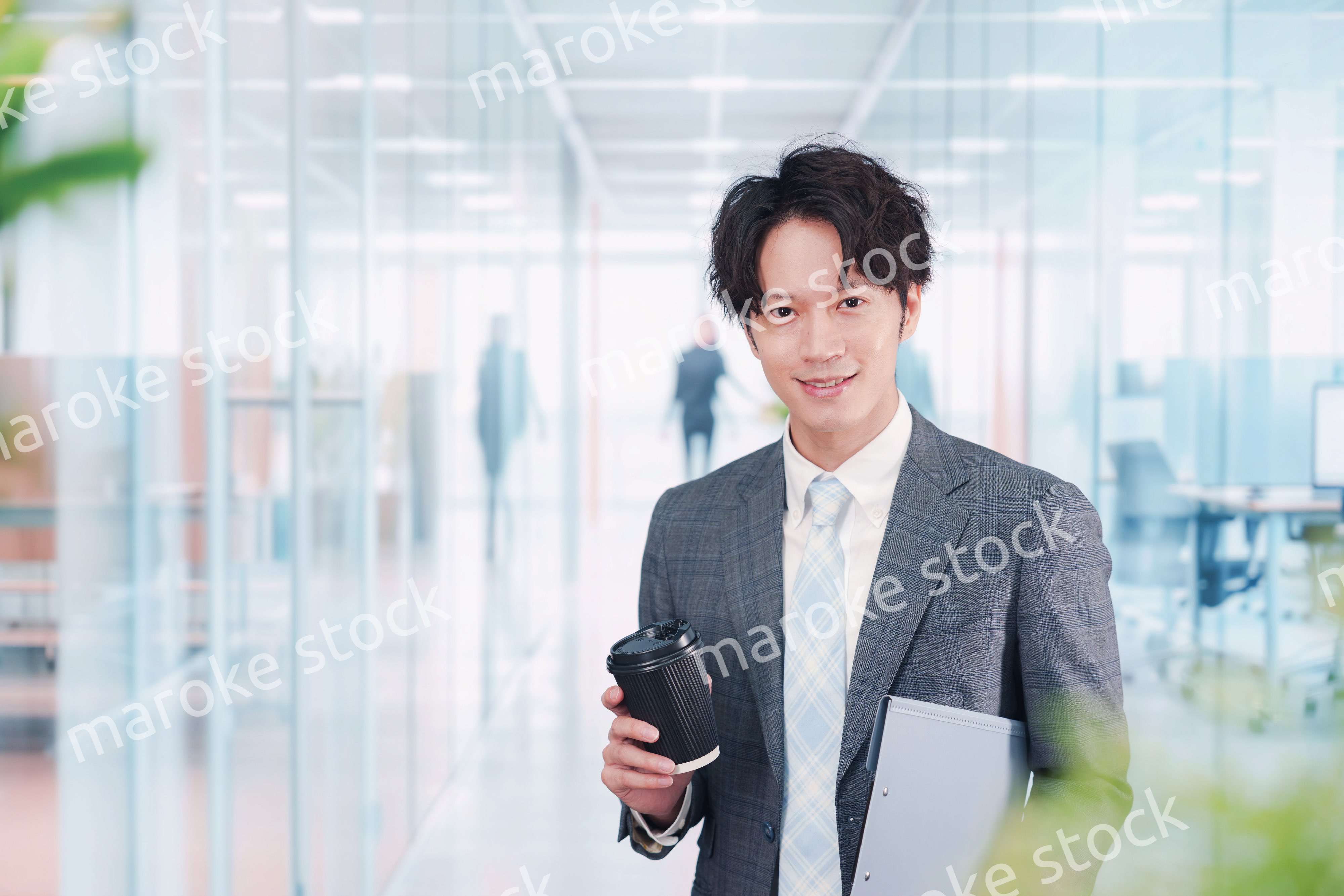 オフィスで紙カップのコーヒーを持って歩くビジネスマン