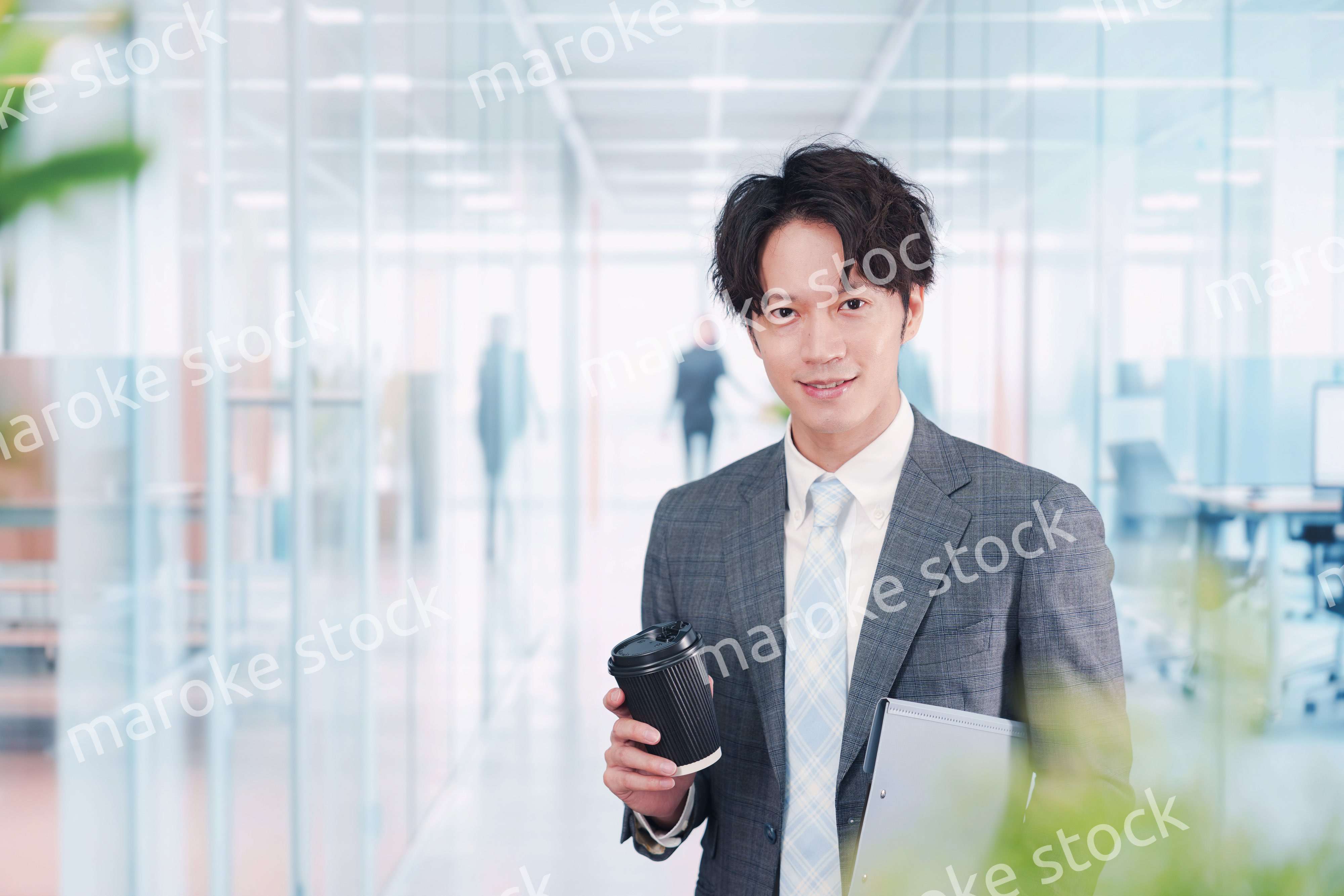 オフィスで紙カップのコーヒーを持って歩くビジネスマン