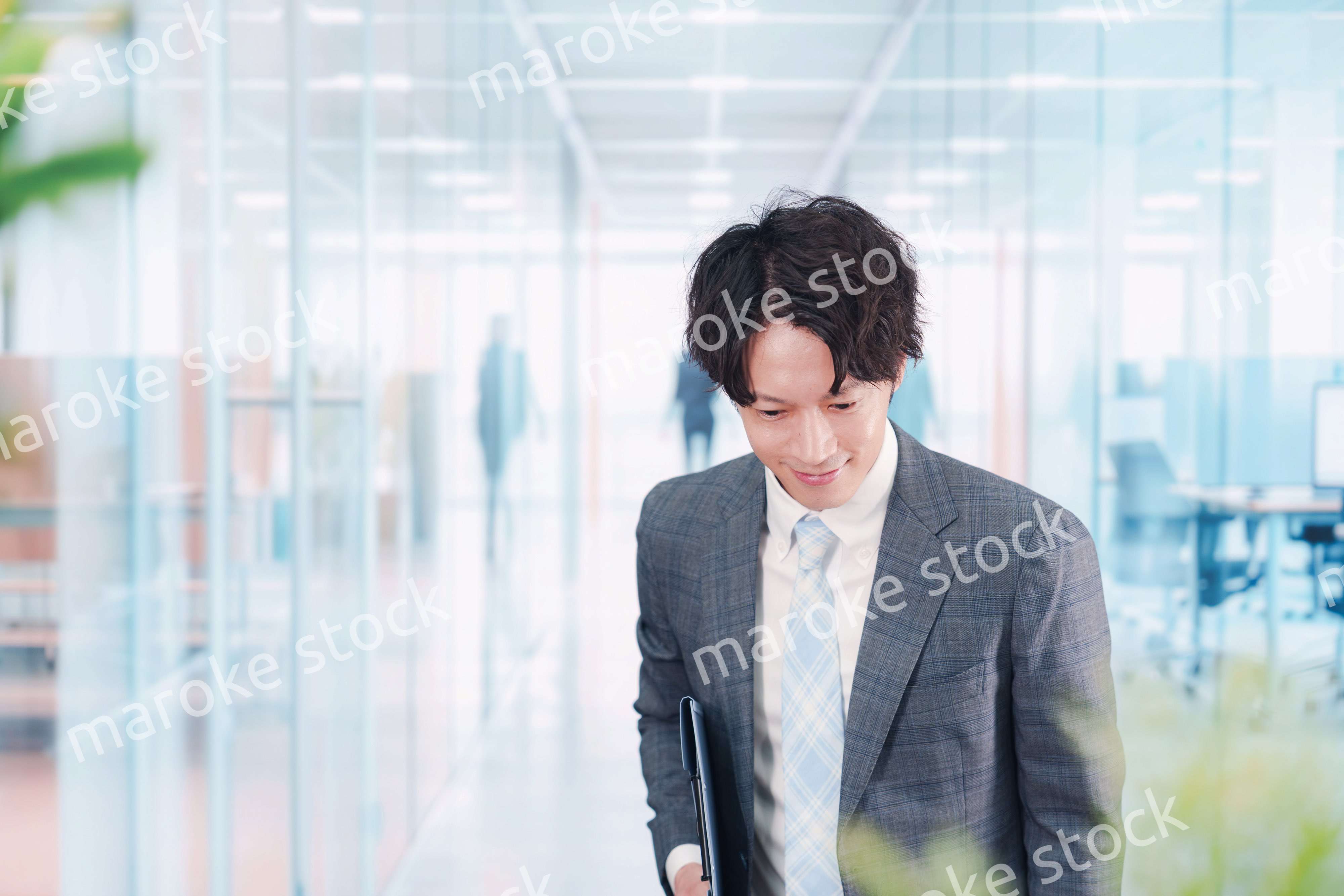 ガラス張りのオフィスの入口でお辞儀をする男性