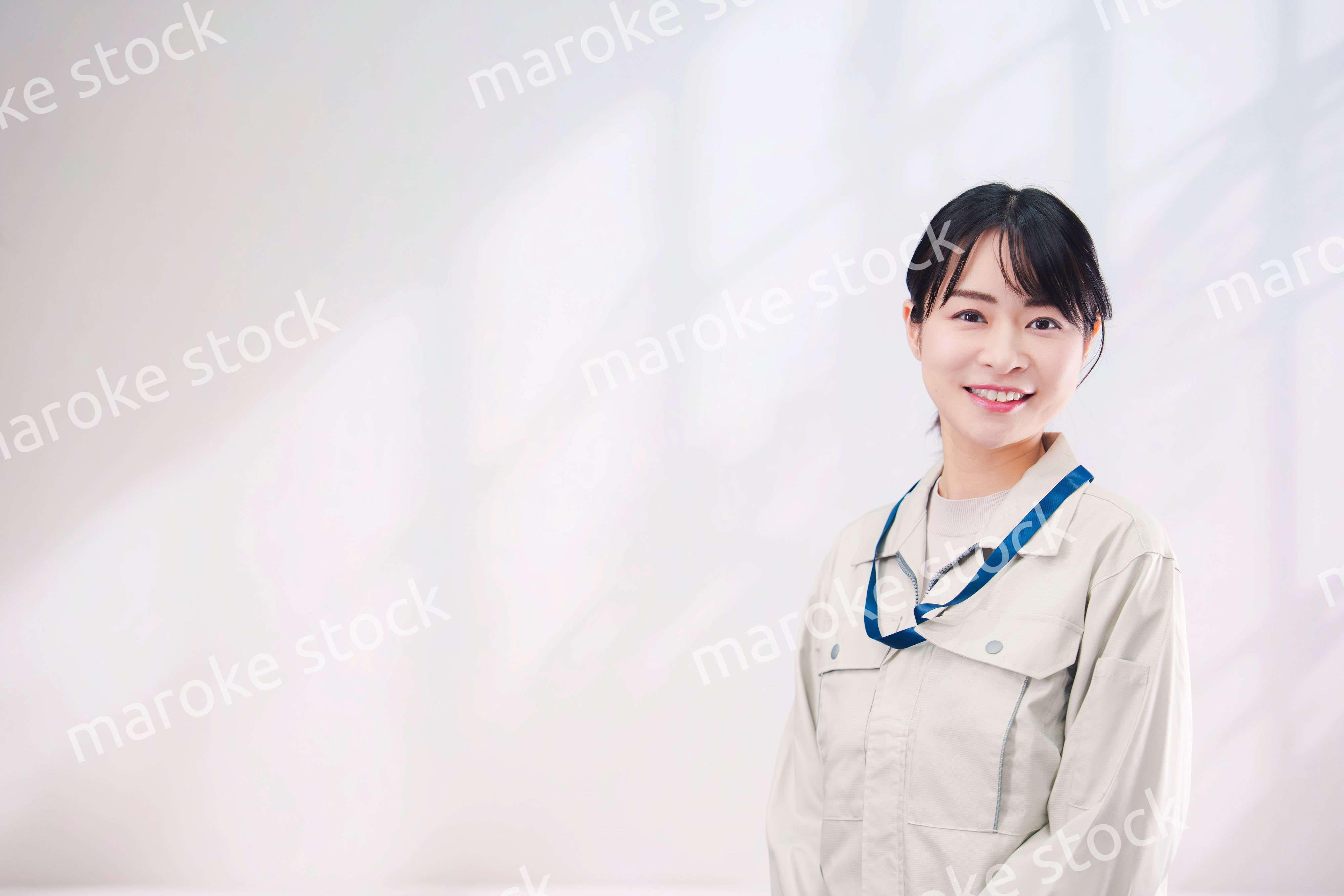 作業服を着て笑顔の若い女性（シンプル背景）