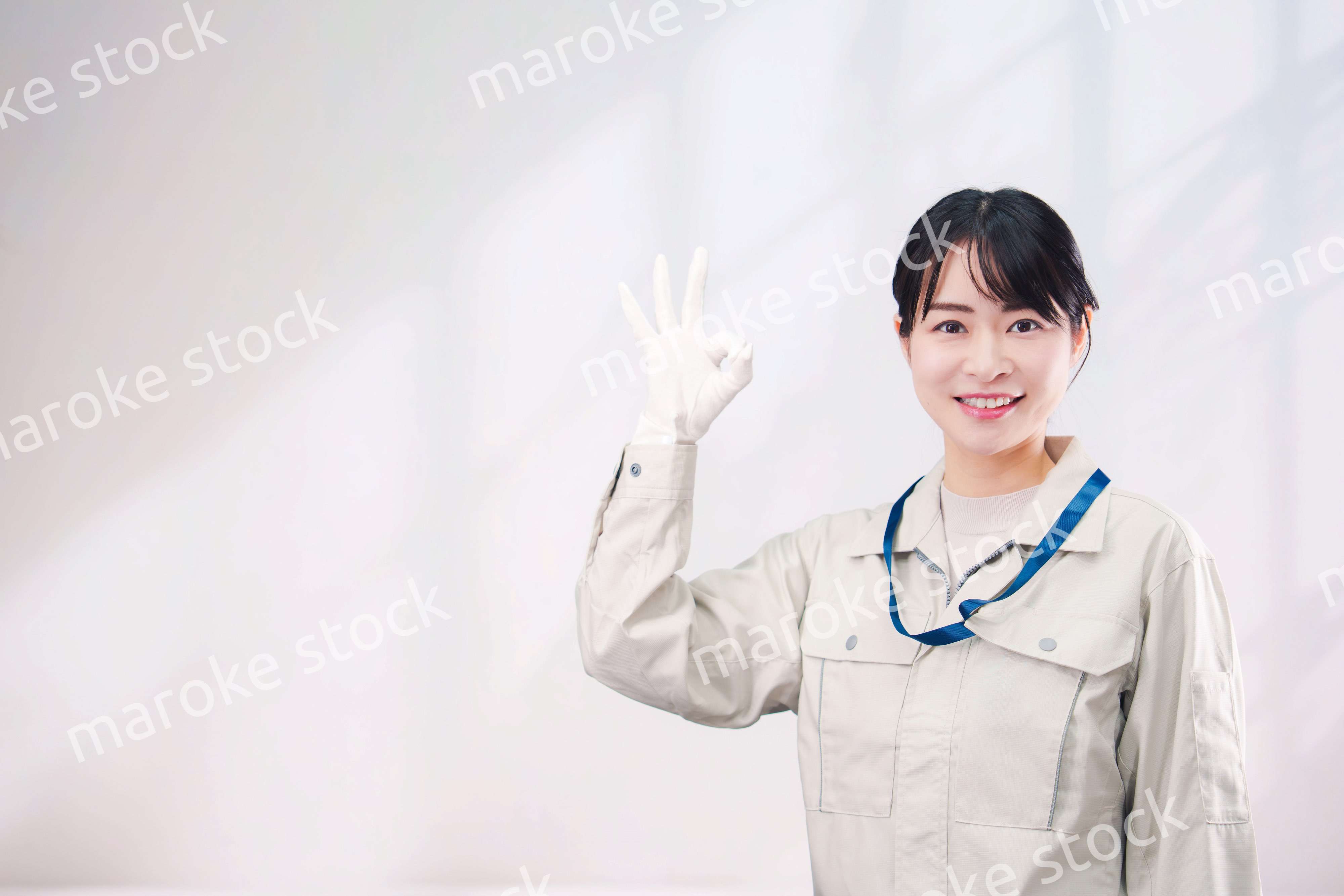作業服を着て笑顔の若い女性（シンプル背景）