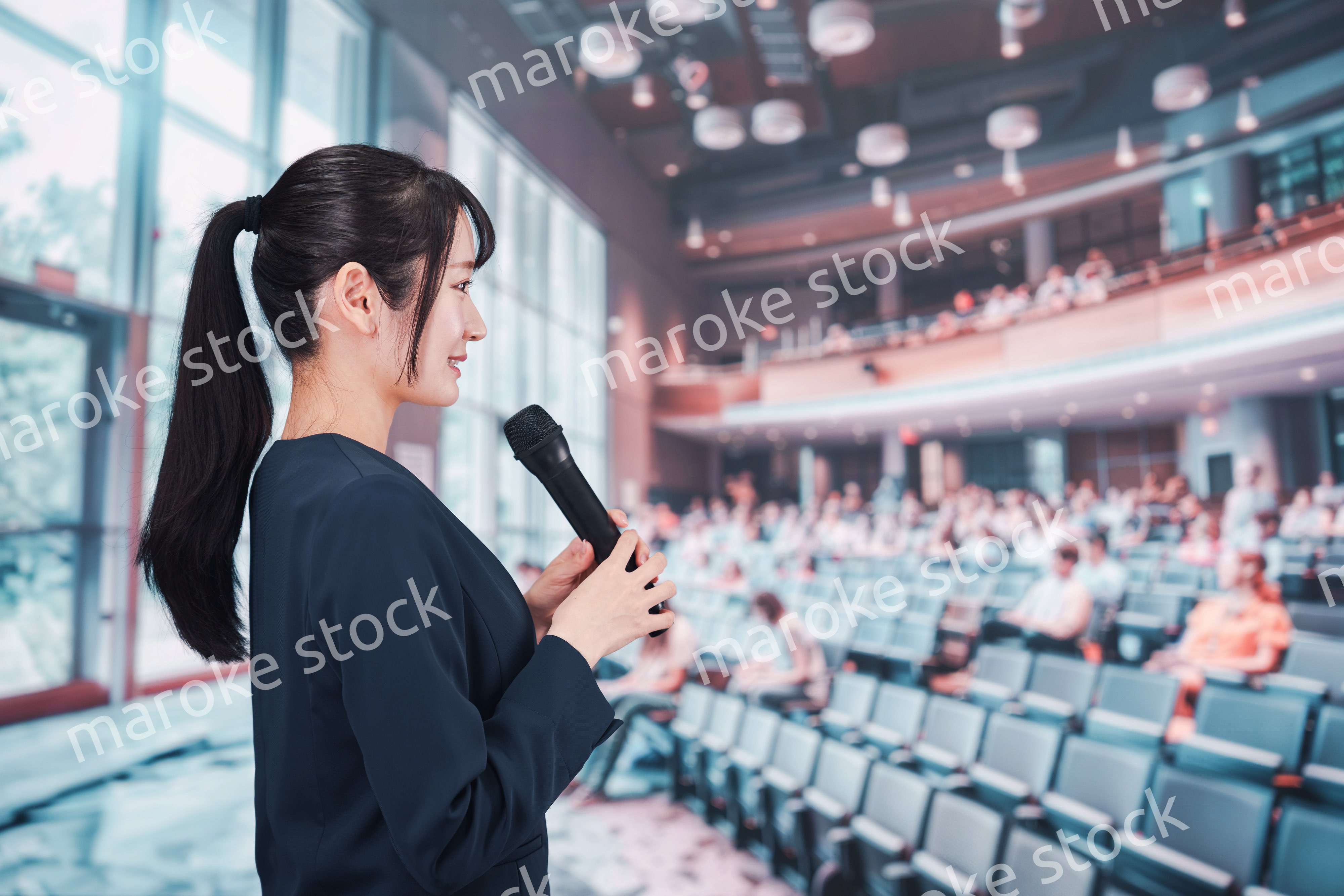 ホールで司会をする若い女性