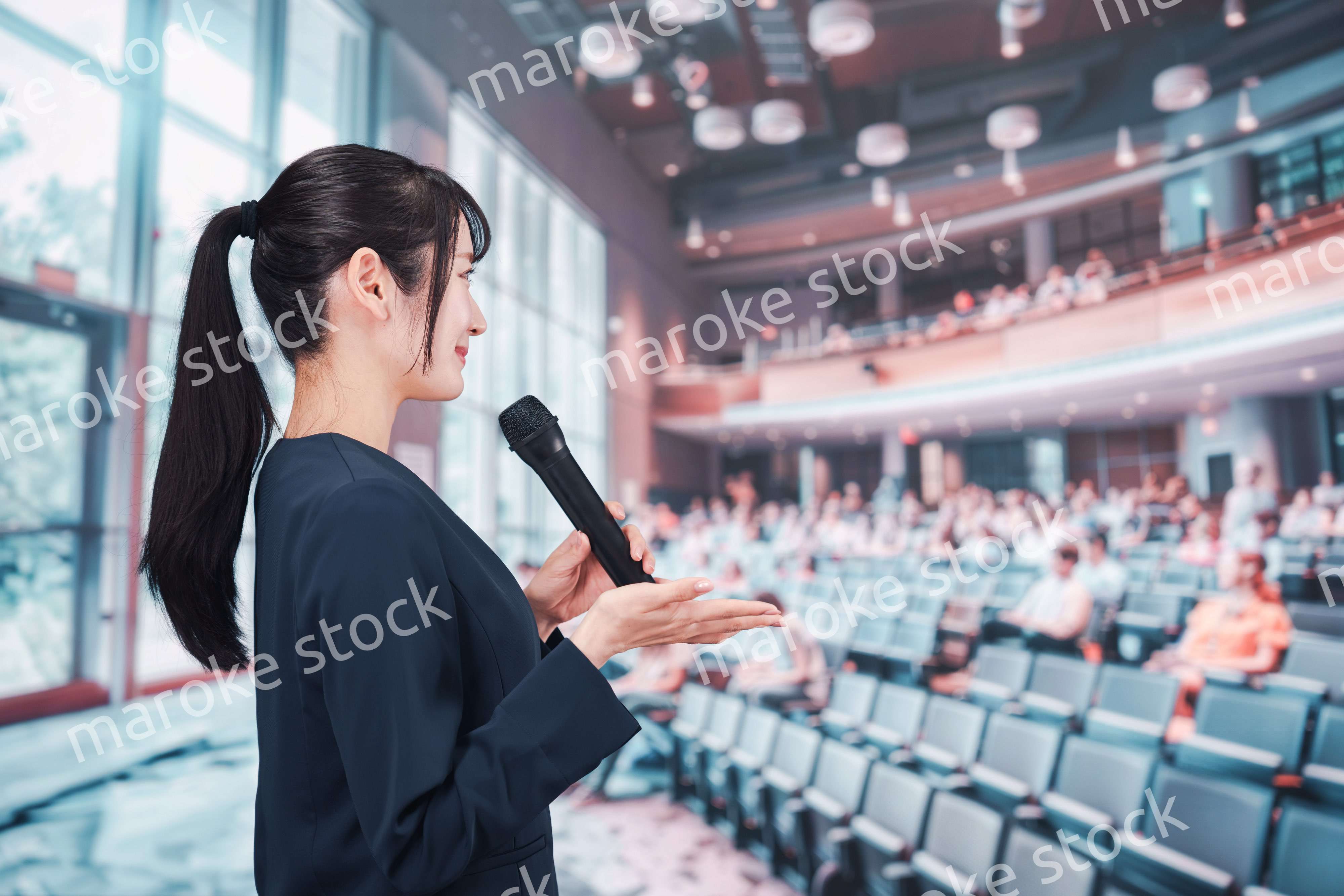 ホールで司会をする若い女性