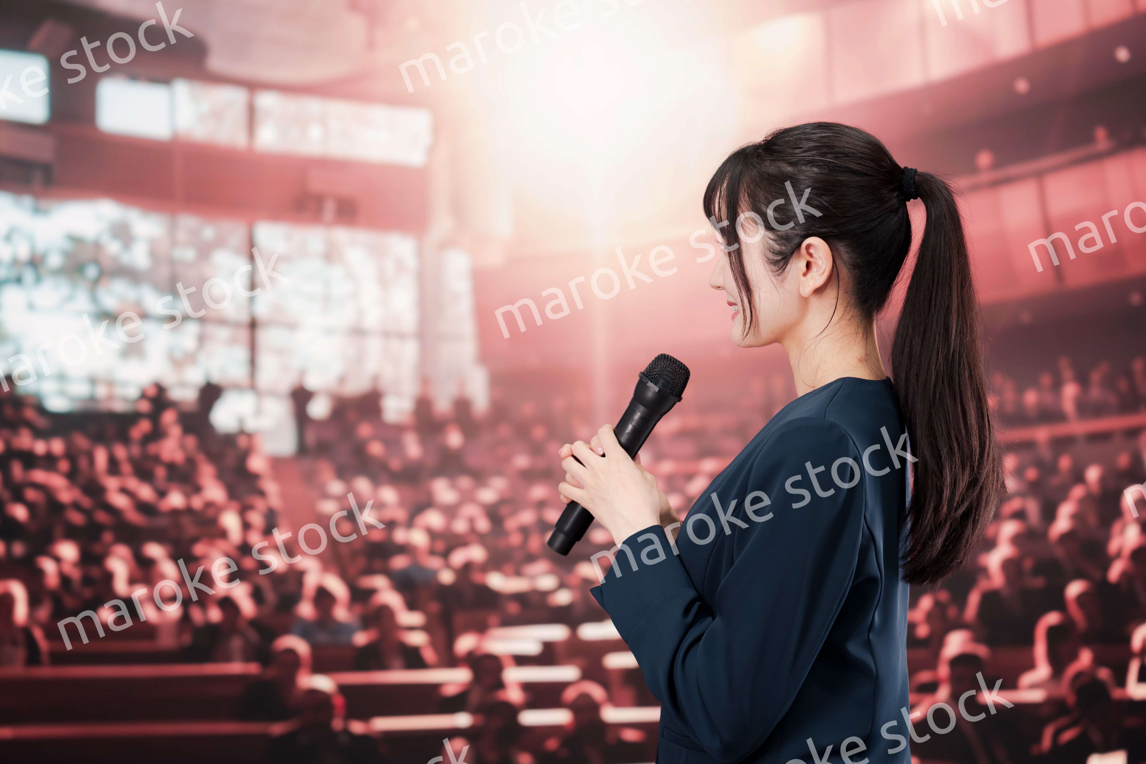 大勢の聴衆の前で話す女性