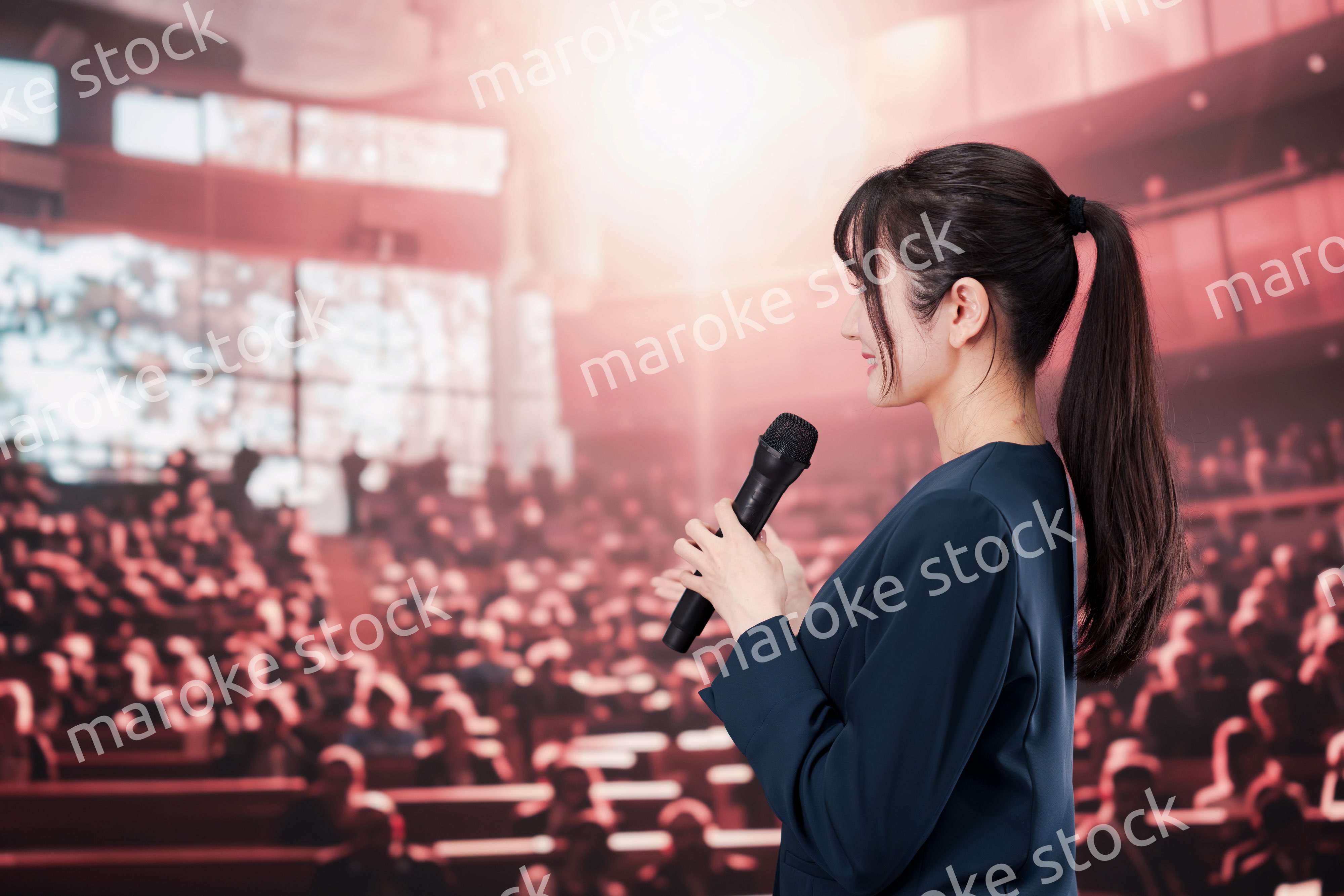 大勢の聴衆の前で話す女性