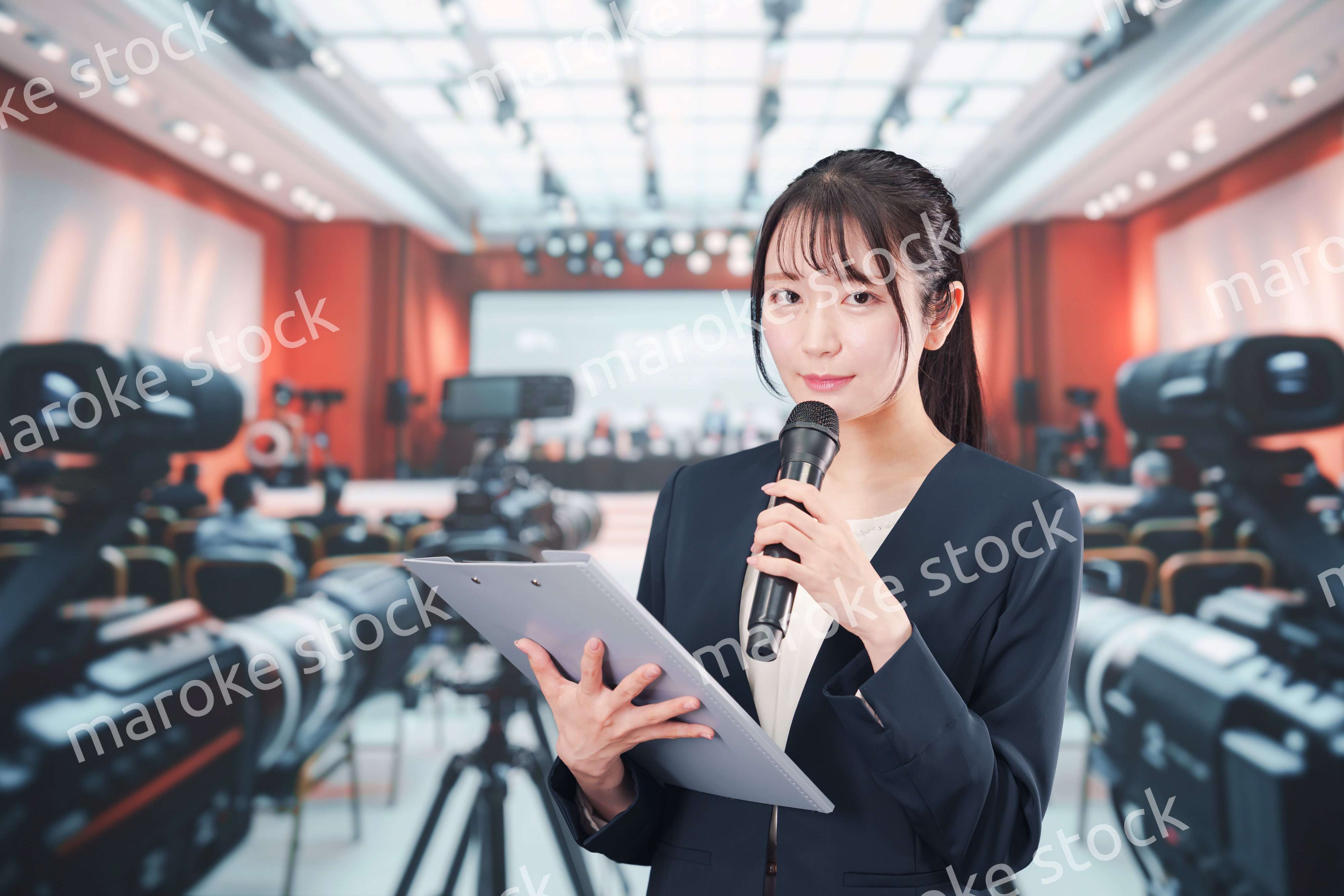 記者会見場からレポートをする女性のアナウンサー