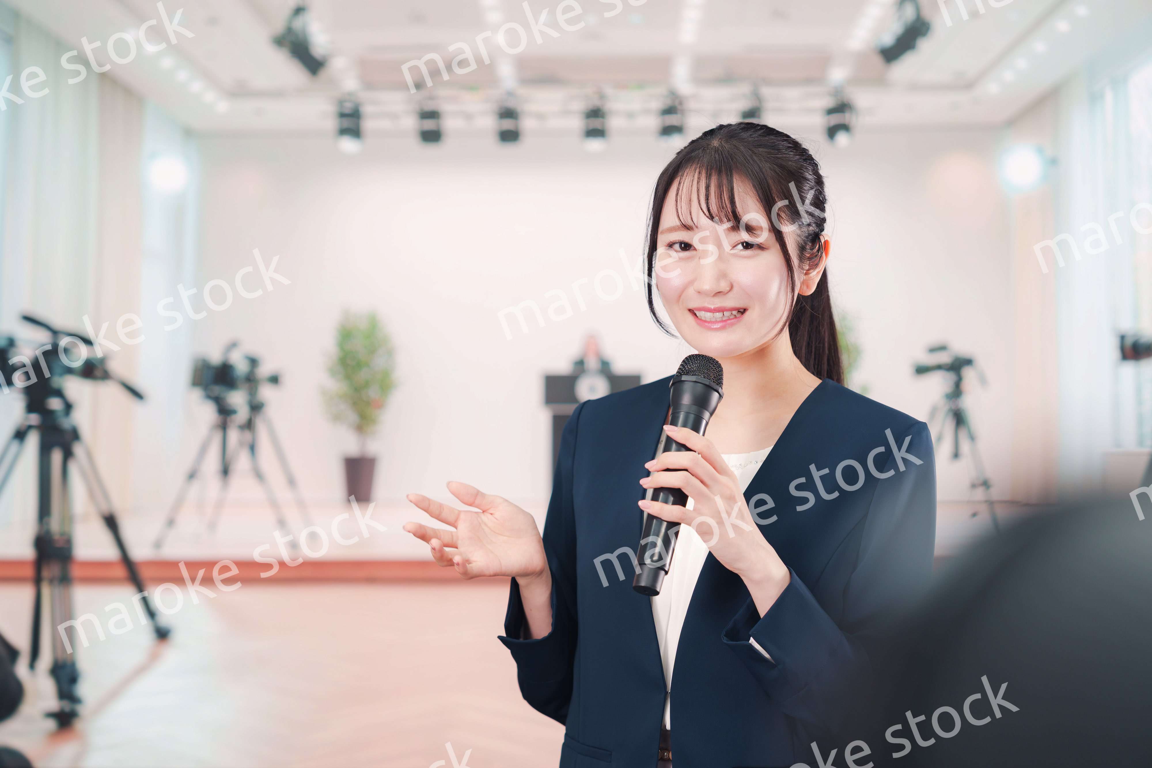 記者会見場からレポートをする女性のアナウンサー