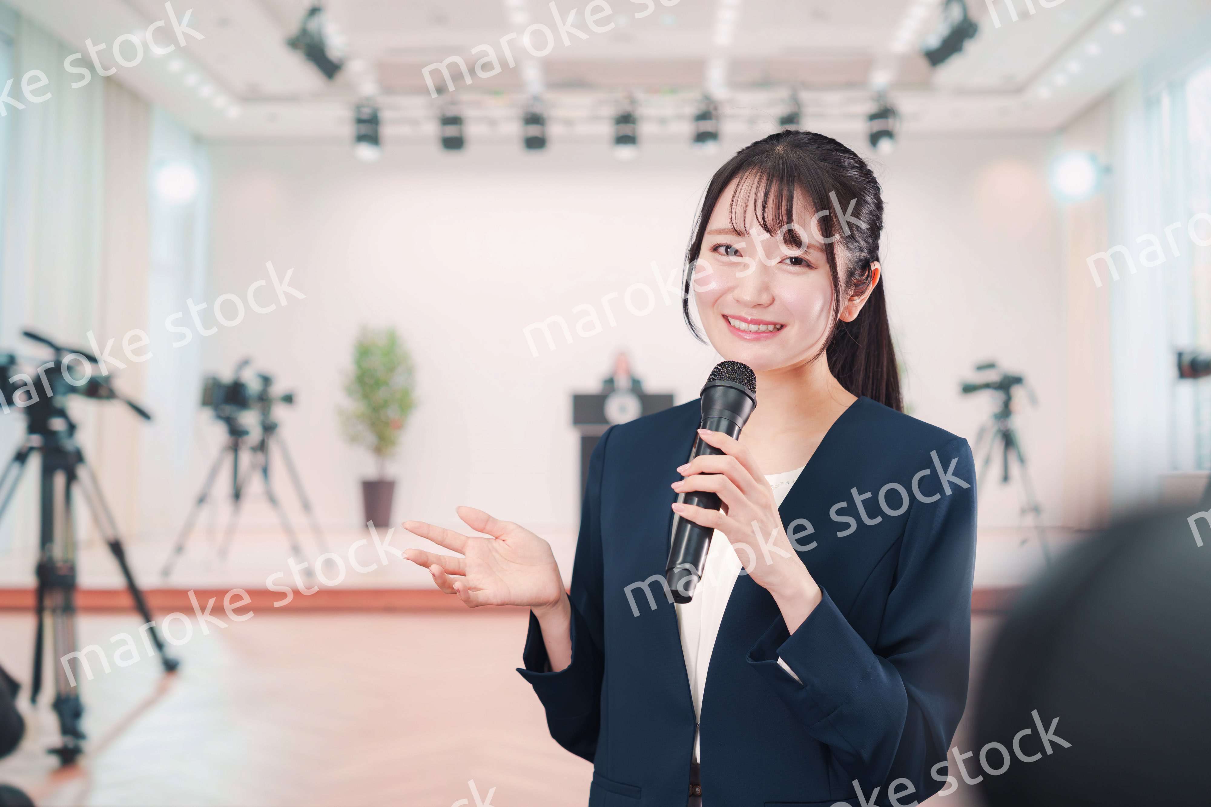 記者会見場からレポートをする女性のアナウンサー