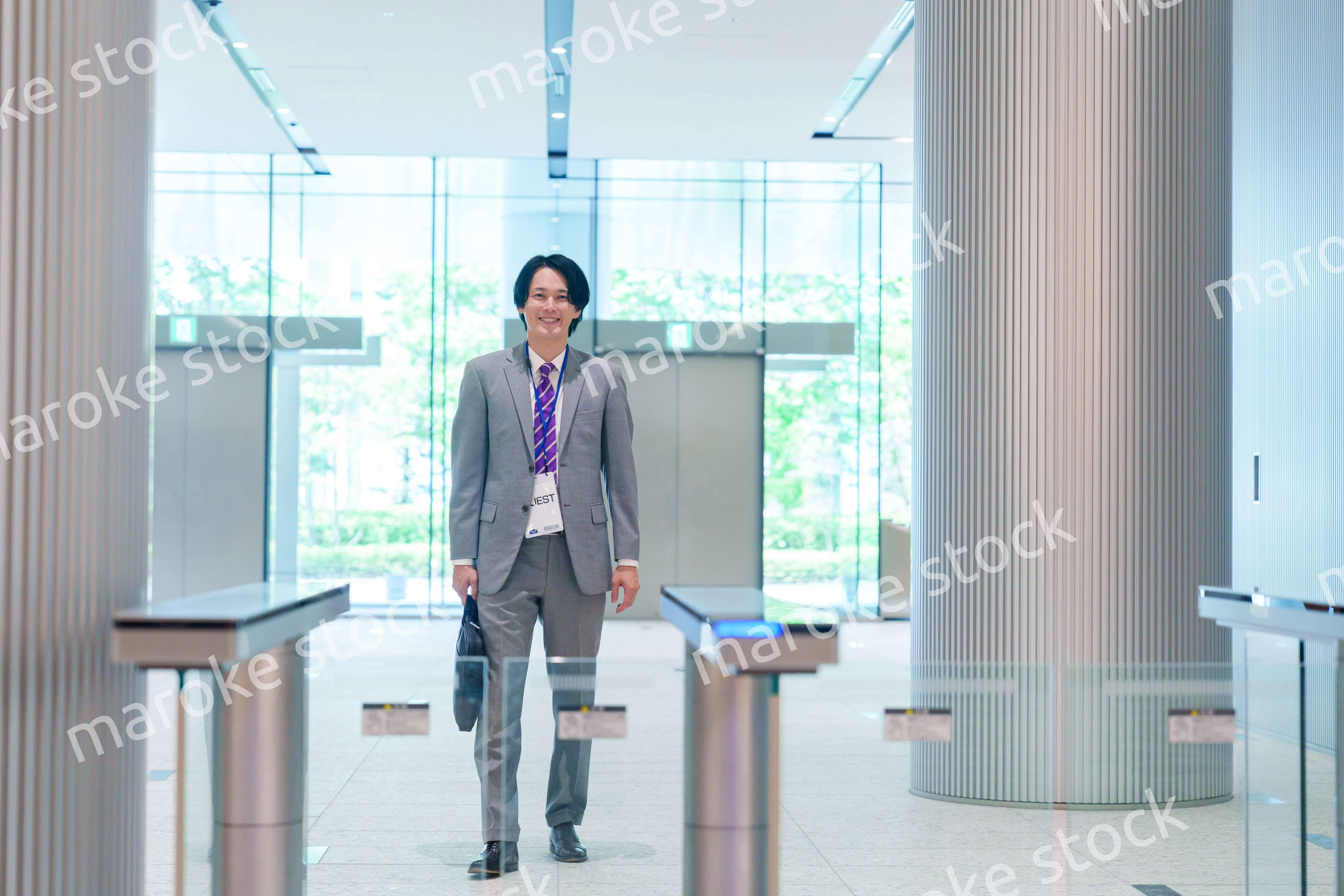 ゲストバッジをつけてビルに入館するビジネスマン