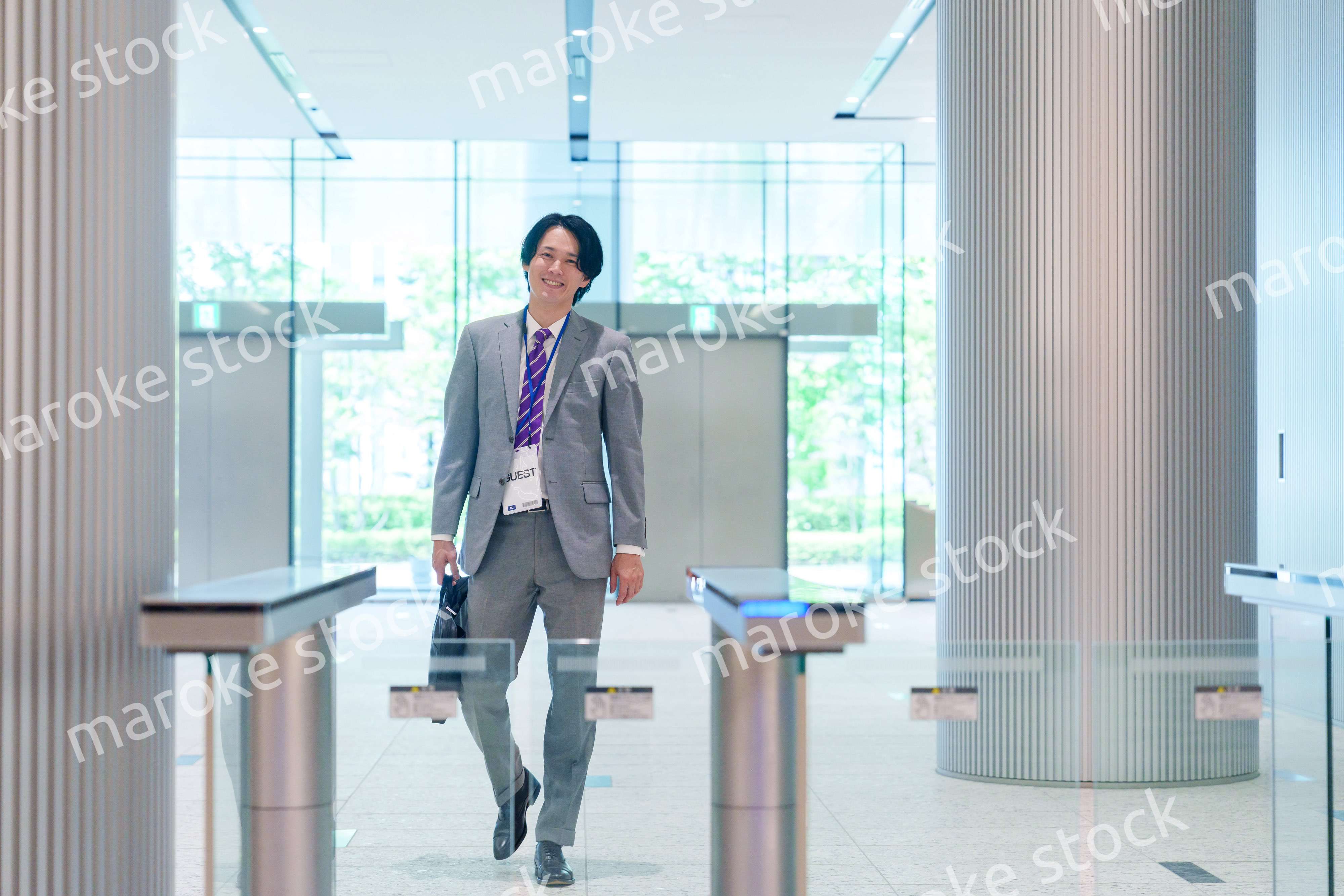 ゲストバッジをつけてビルに入館するビジネスマン