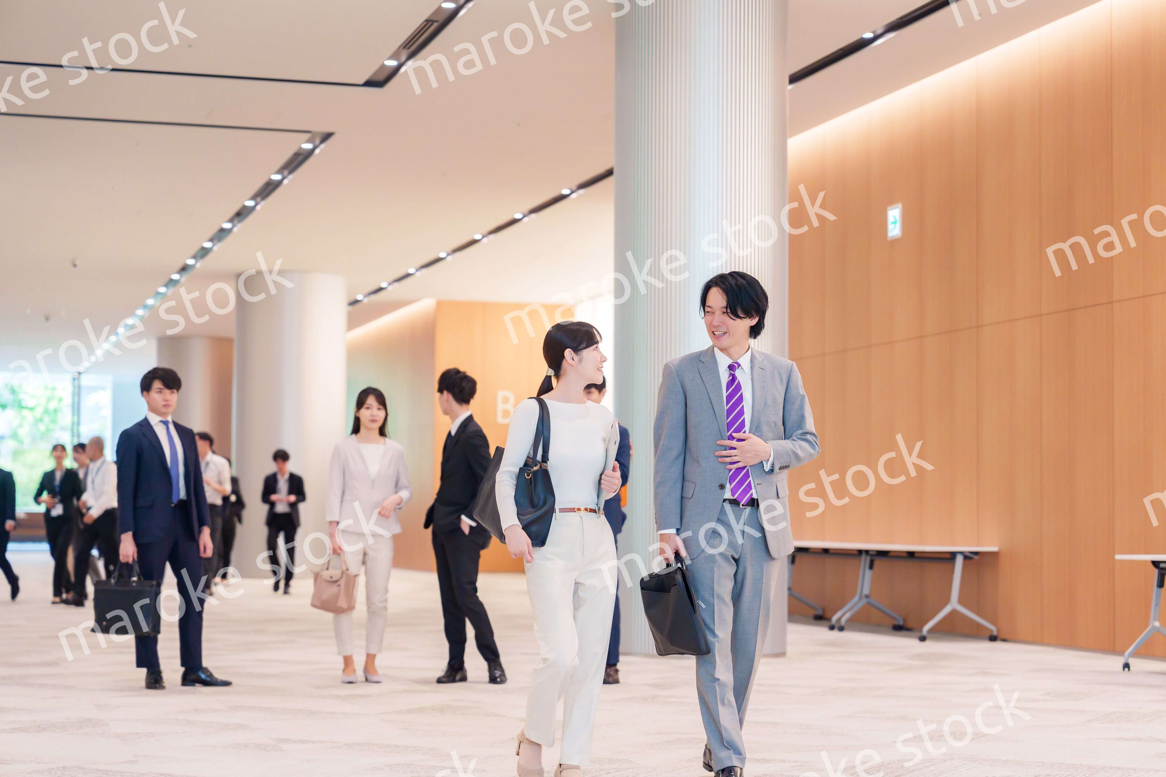 オフィスのホールで話しながら歩くビジネスパーソン