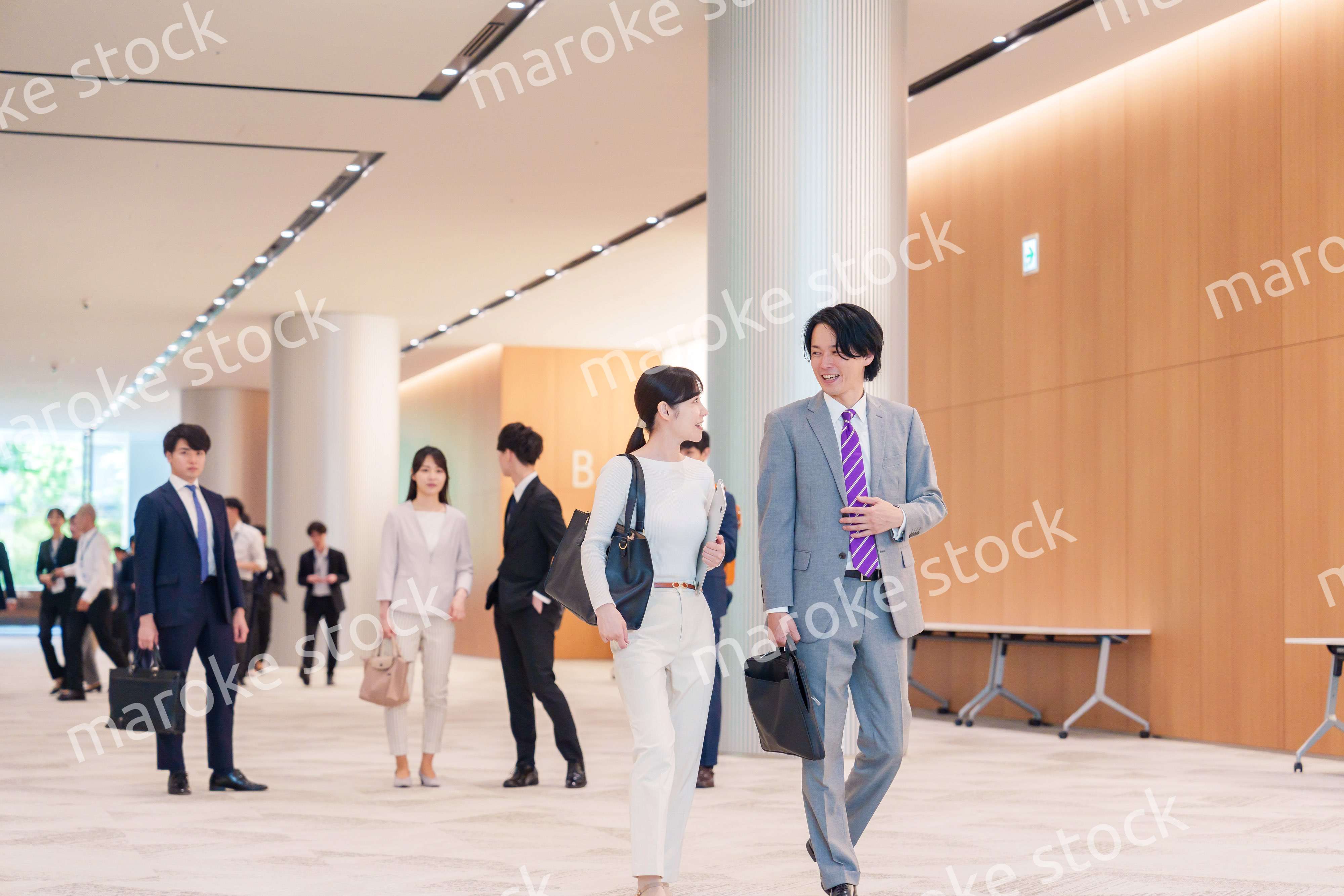 オフィスのホールで話しながら歩くビジネスパーソン