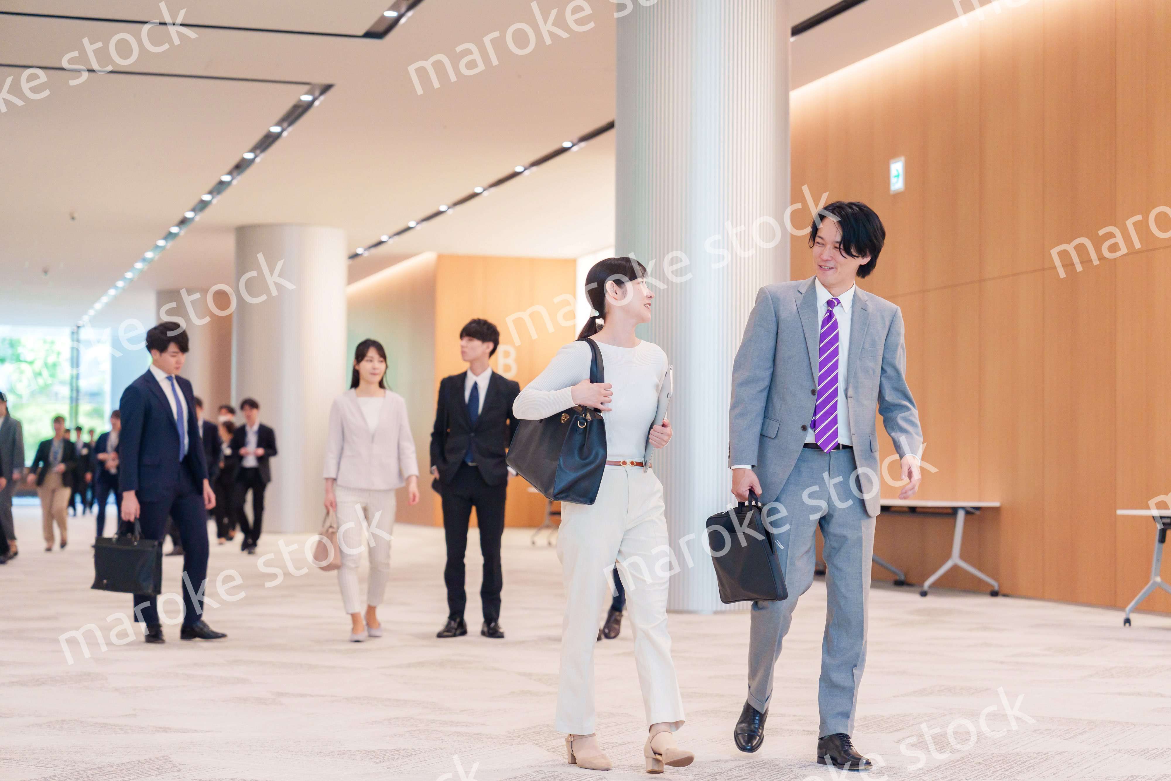 オフィスのホールで話しながら歩くビジネスパーソン