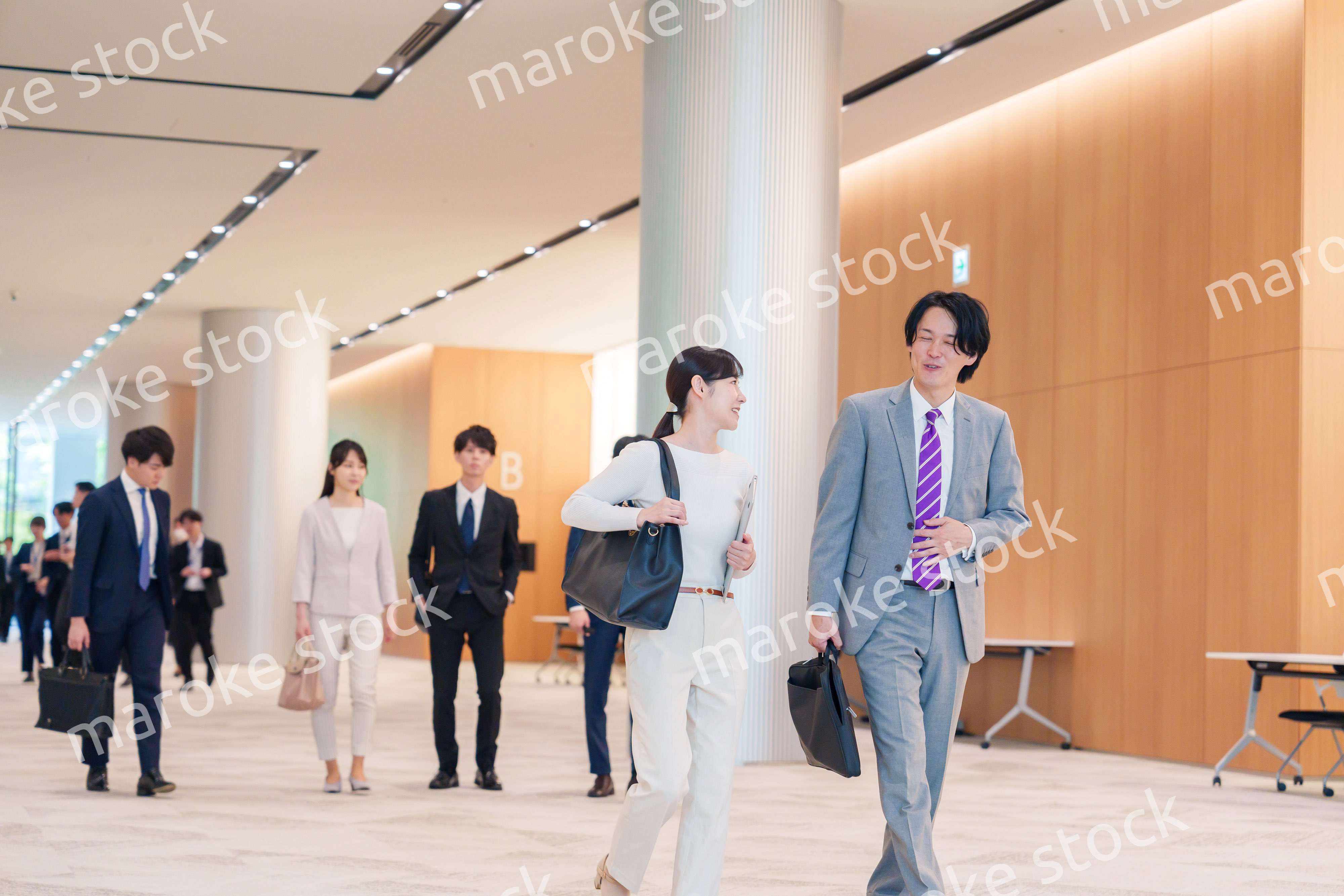 オフィスのホールで話しながら歩くビジネスパーソン