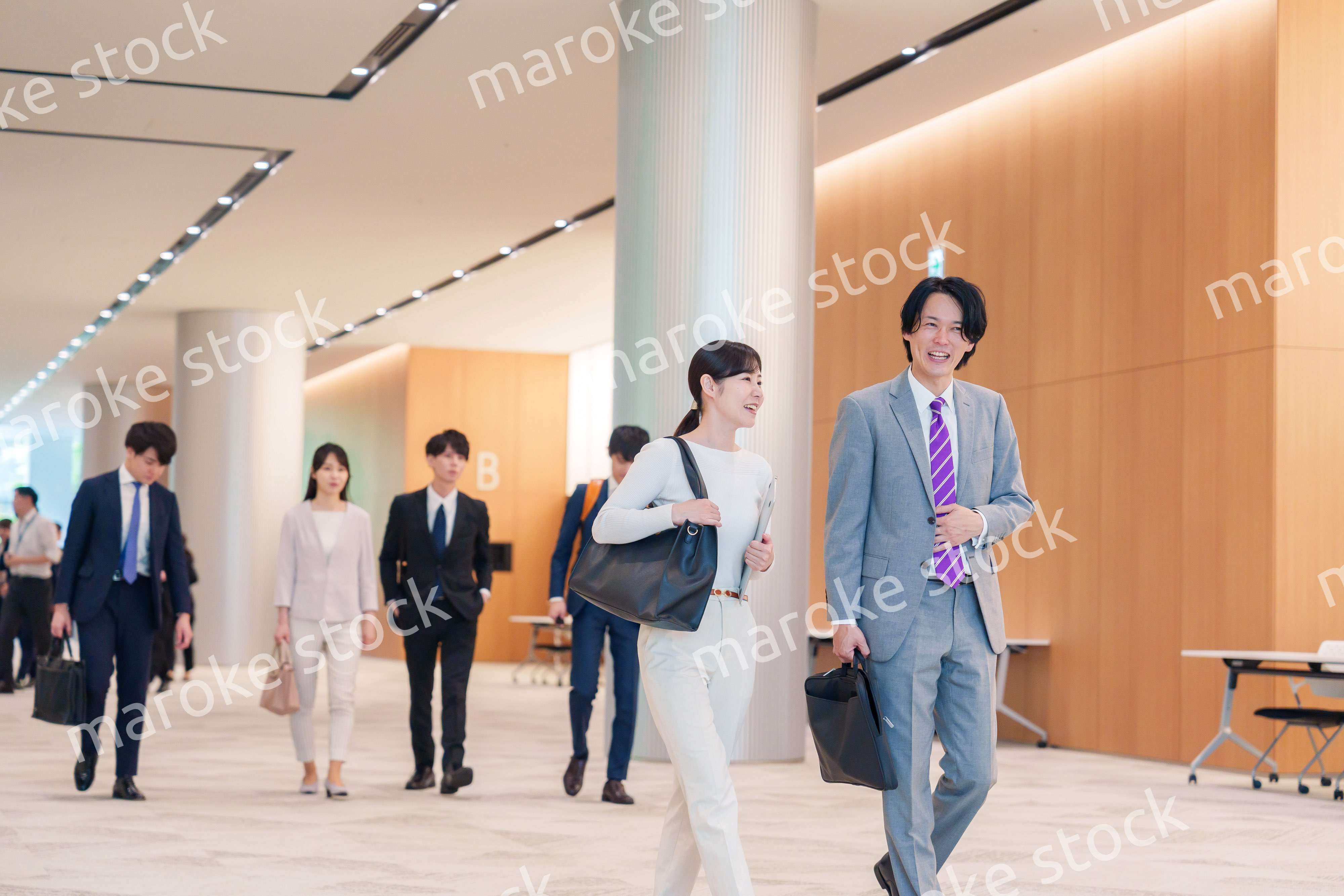 オフィスのホールで話しながら歩くビジネスパーソン