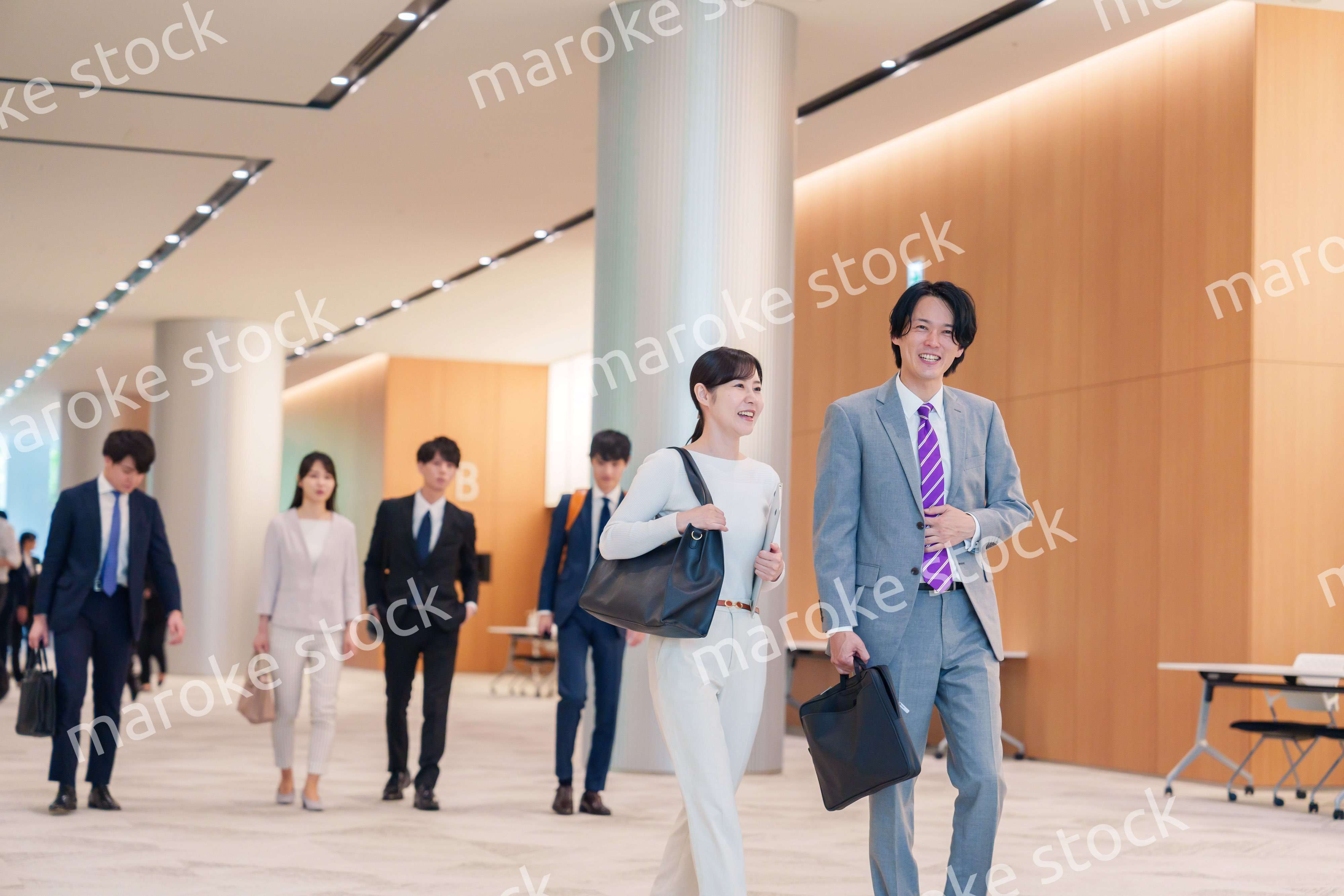 オフィスのホールで話しながら歩くビジネスパーソン