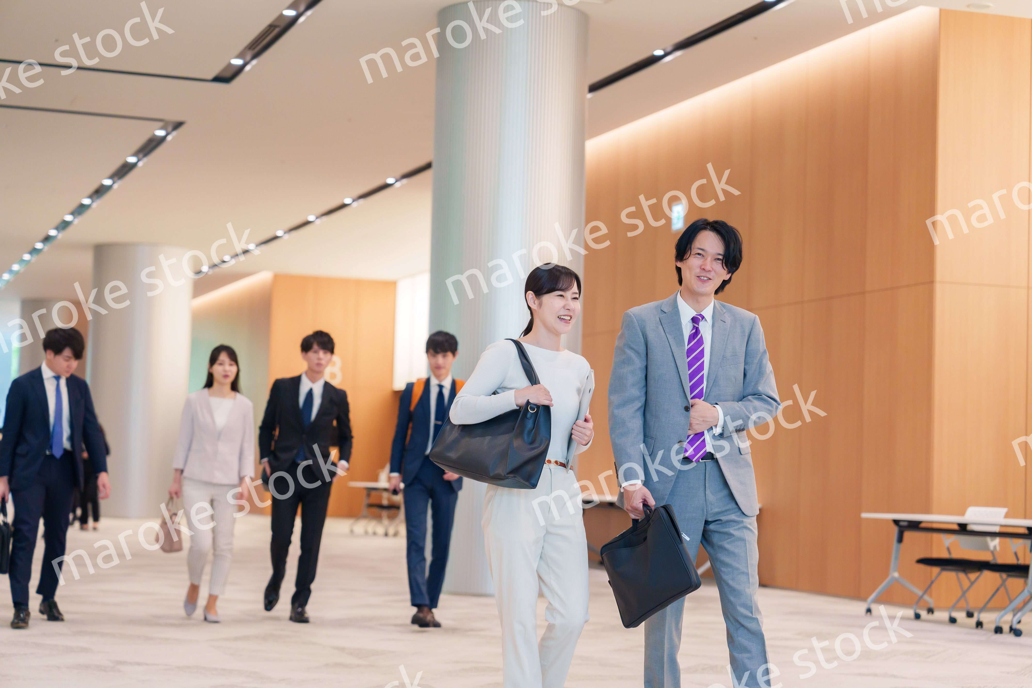 オフィスのホールで話しながら歩くビジネスパーソン