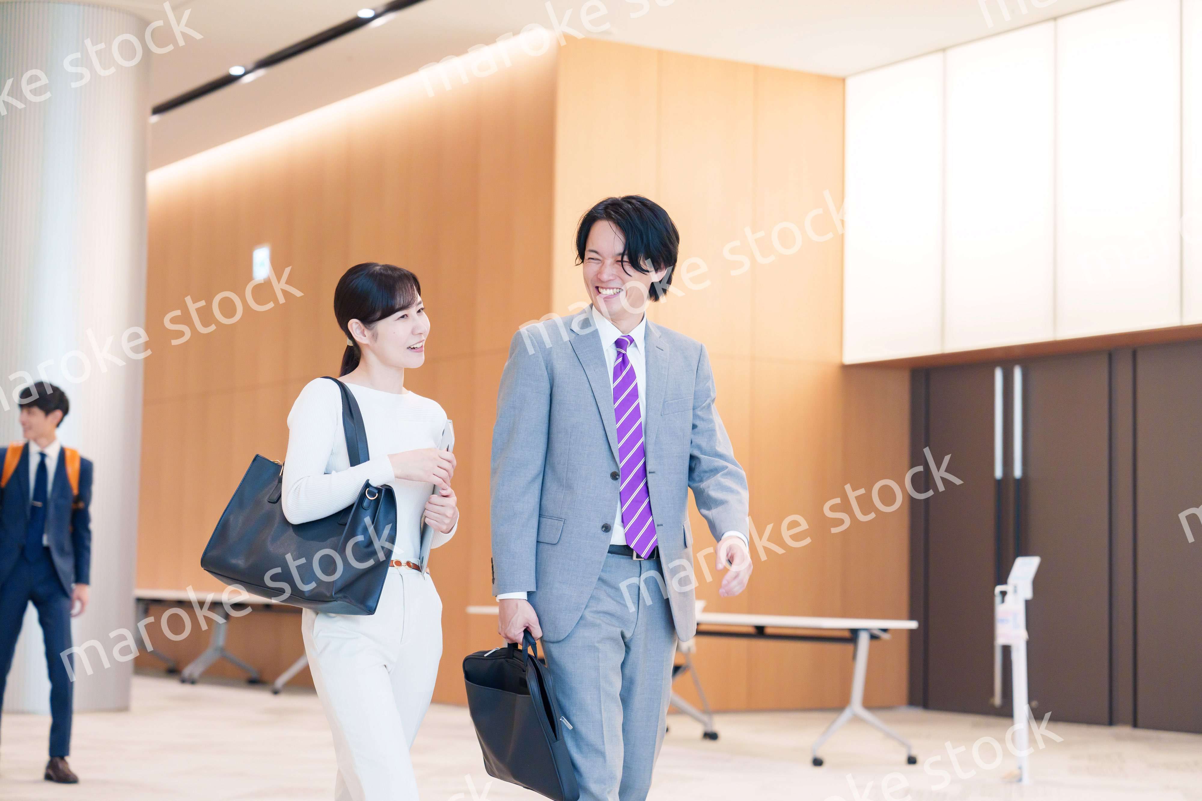 オフィスのホールで話しながら歩くビジネスパーソン
