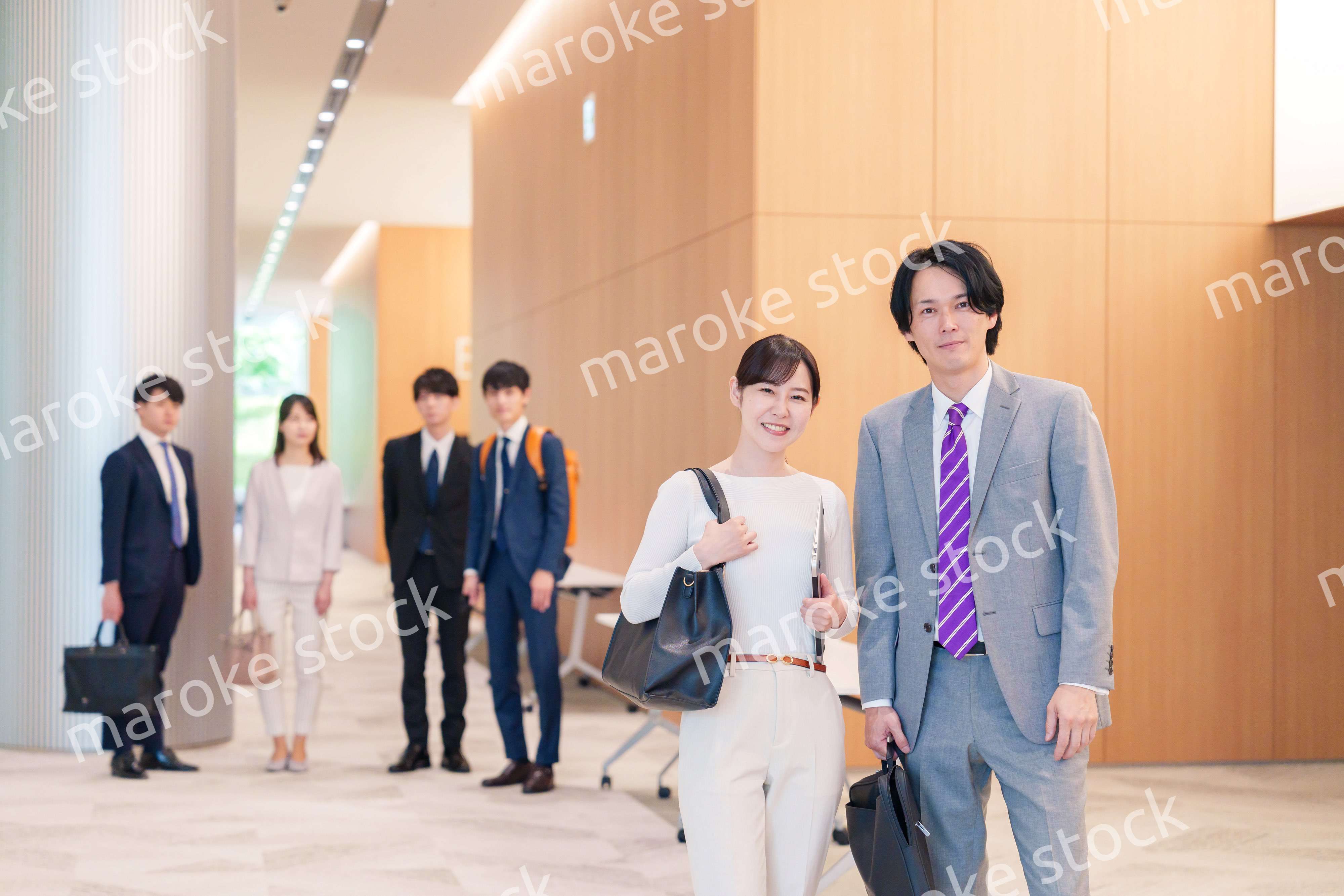 オフィスのホールで話しながら歩くビジネスパーソン