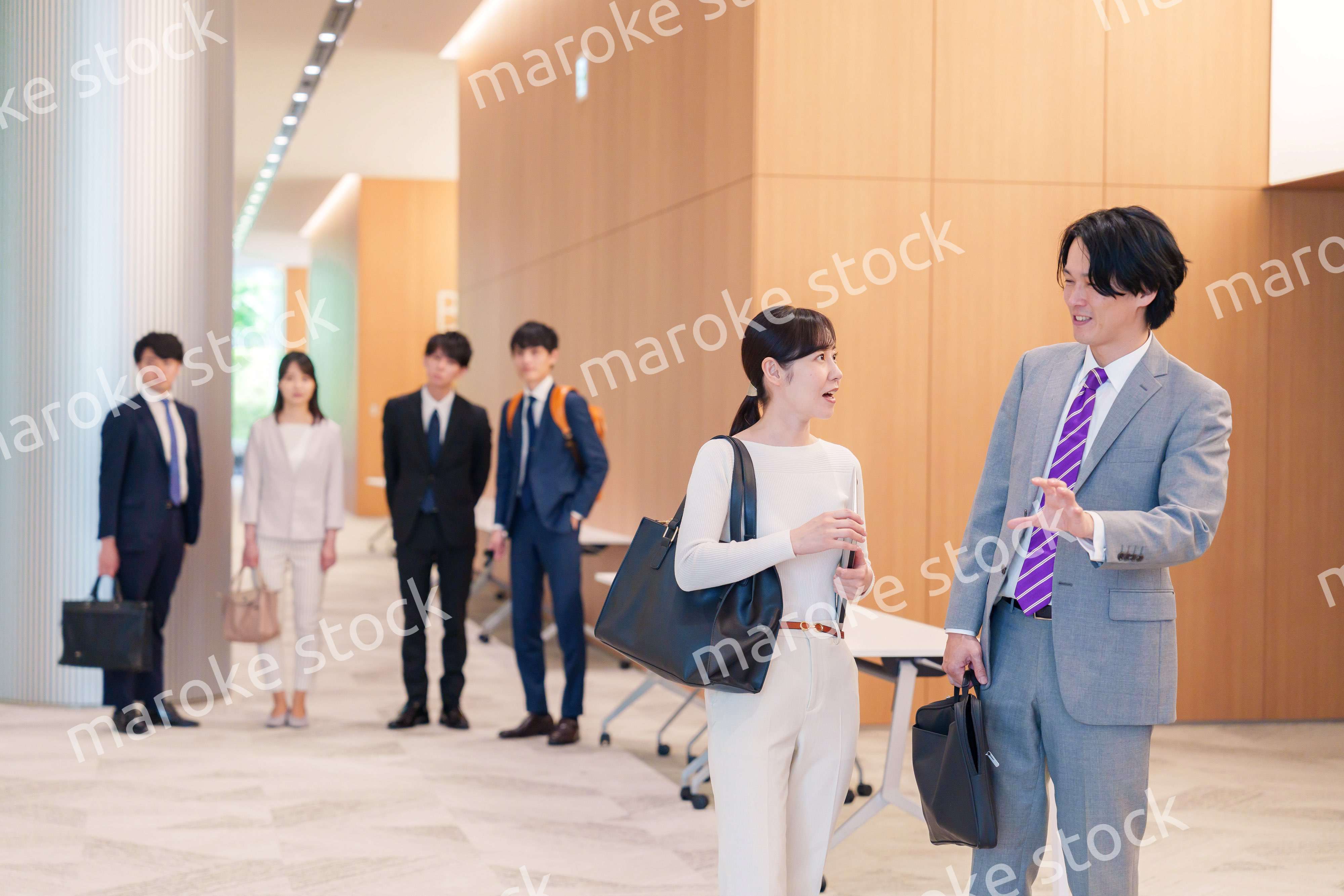 オフィスのホールで話しながら歩くビジネスパーソン
