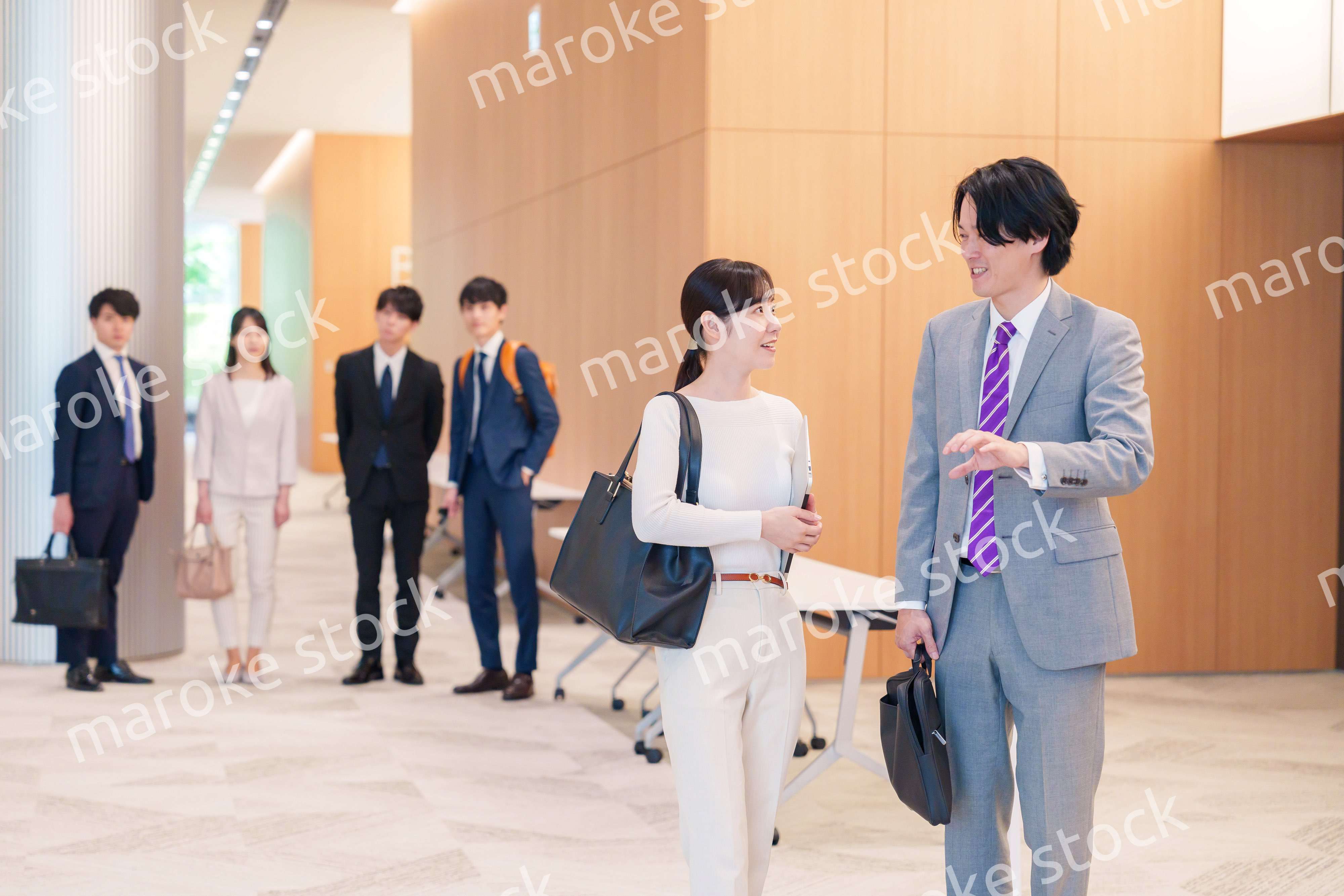 オフィスのホールで話しながら歩くビジネスパーソン