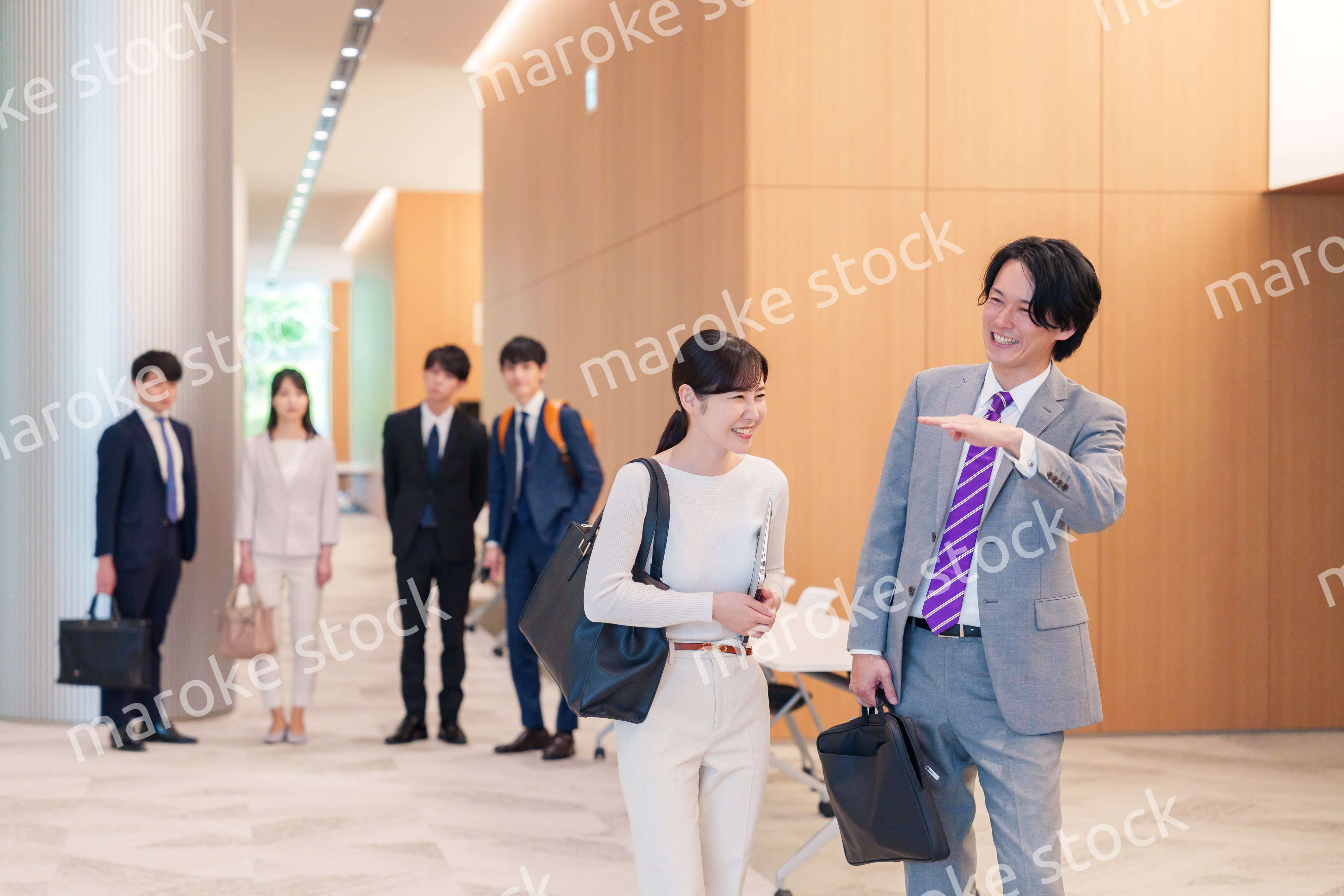 オフィスのホールで話しながら歩くビジネスパーソン