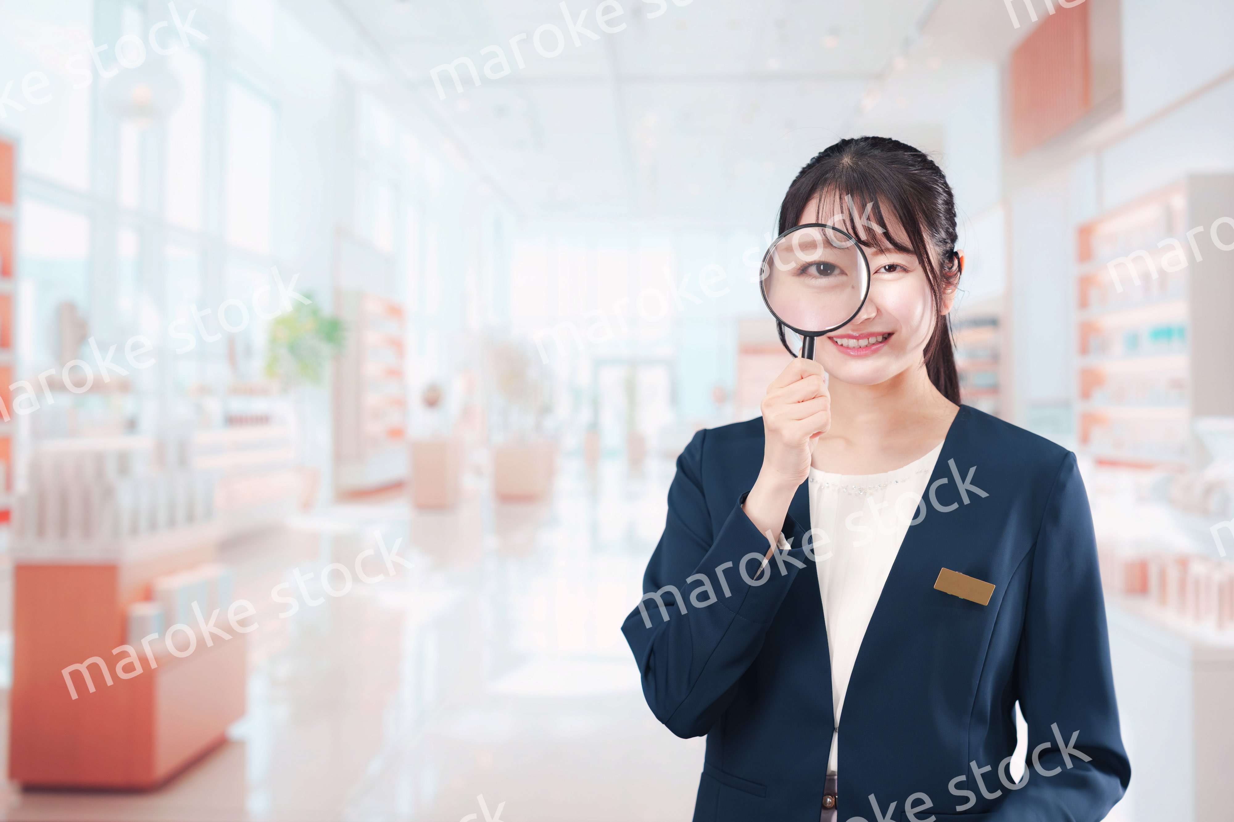 笑顔でルーペを持つ美容部員の女性