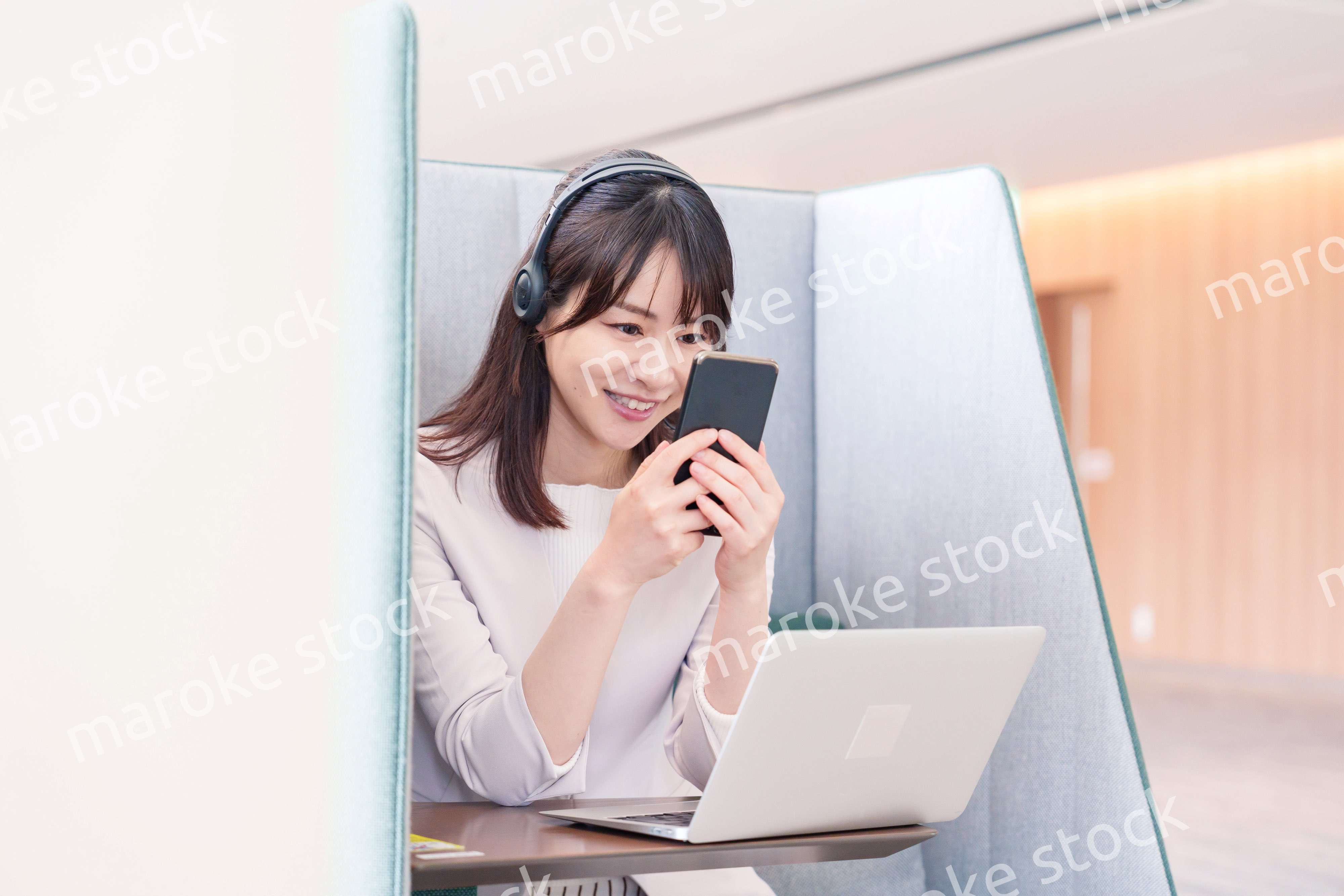 リモート会議をサボってスマホを使う若いビジネスパーソン