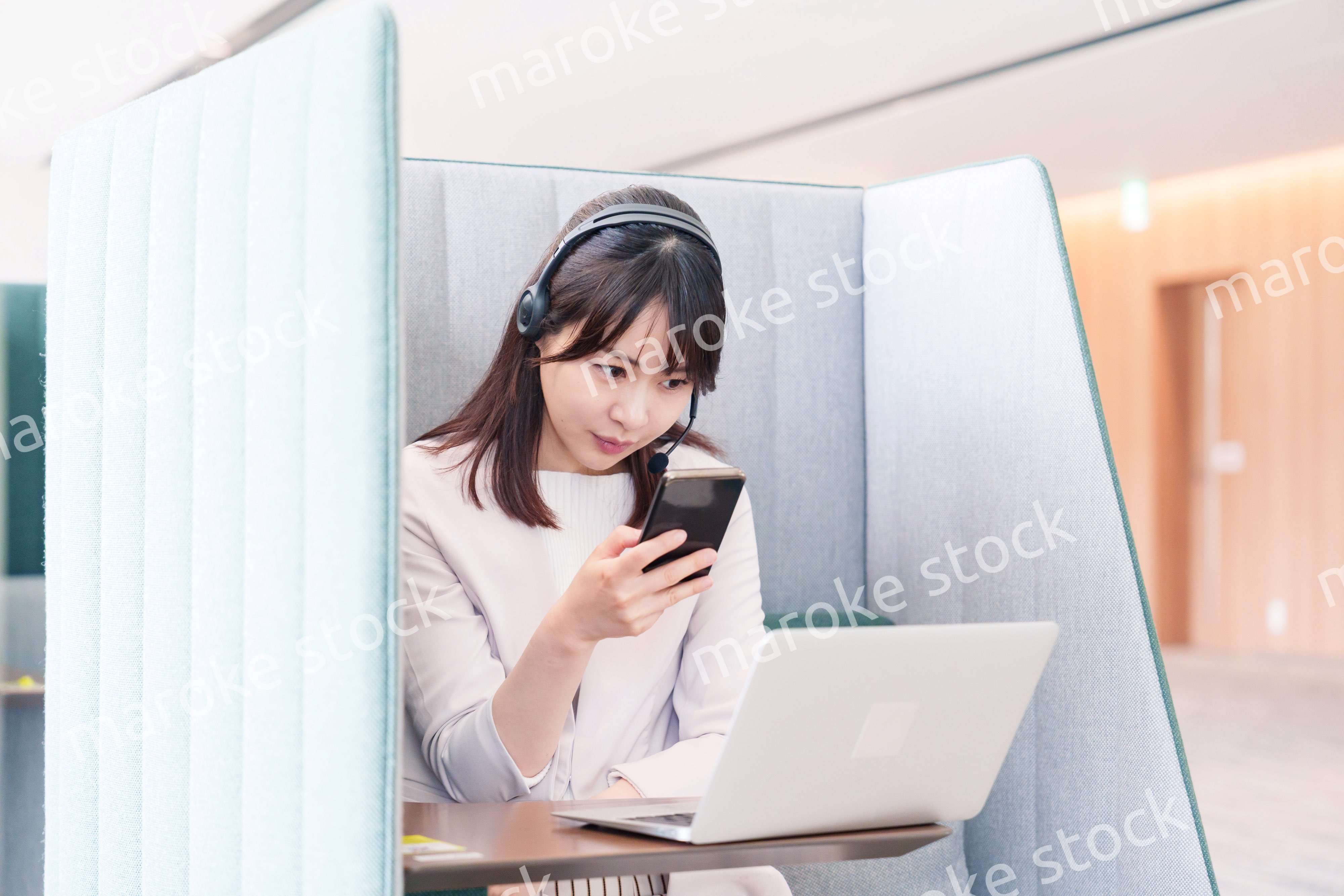 リモート会議をサボってスマホを使う若いビジネスパーソン