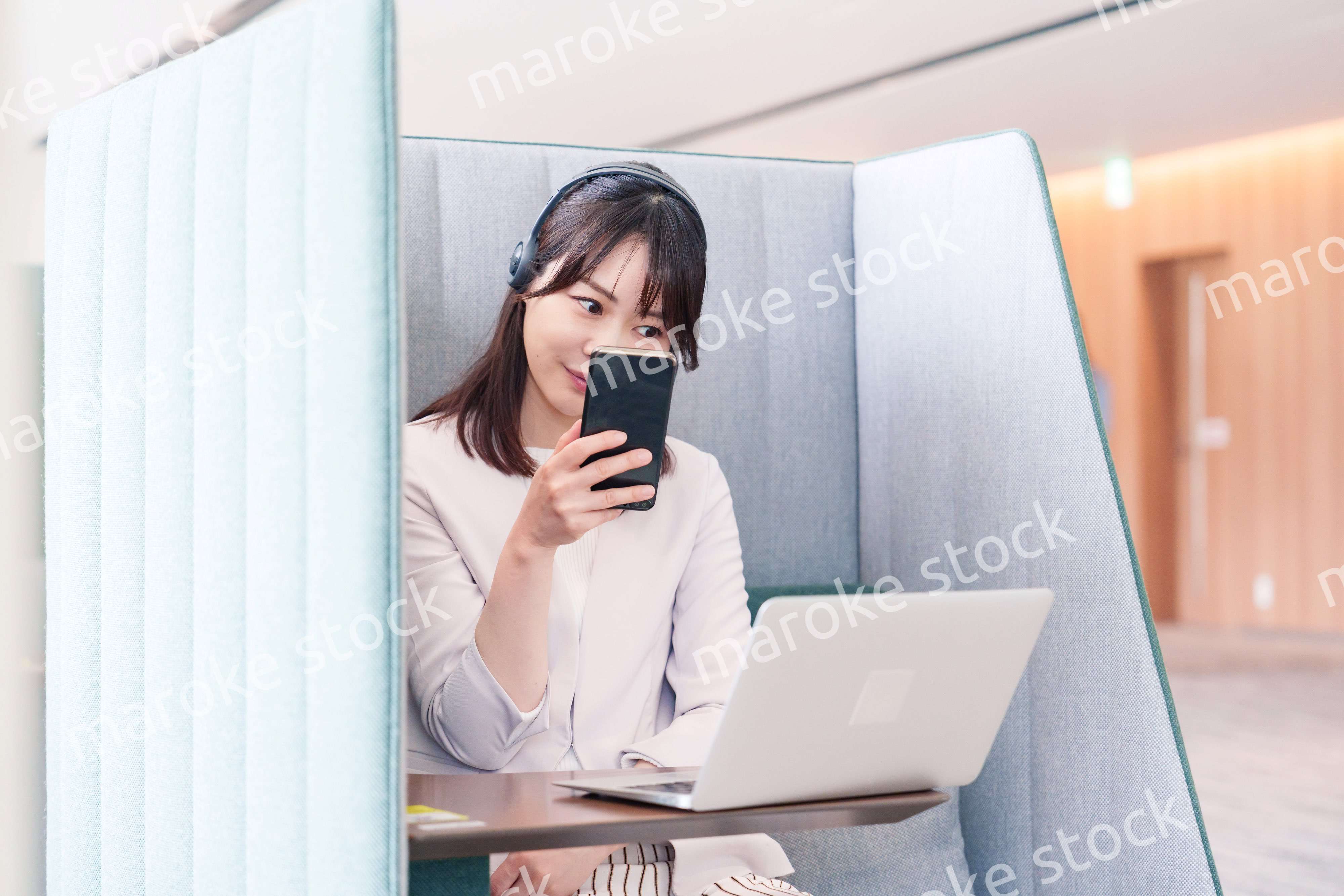 リモート会議をサボってスマホを使う若いビジネスパーソン