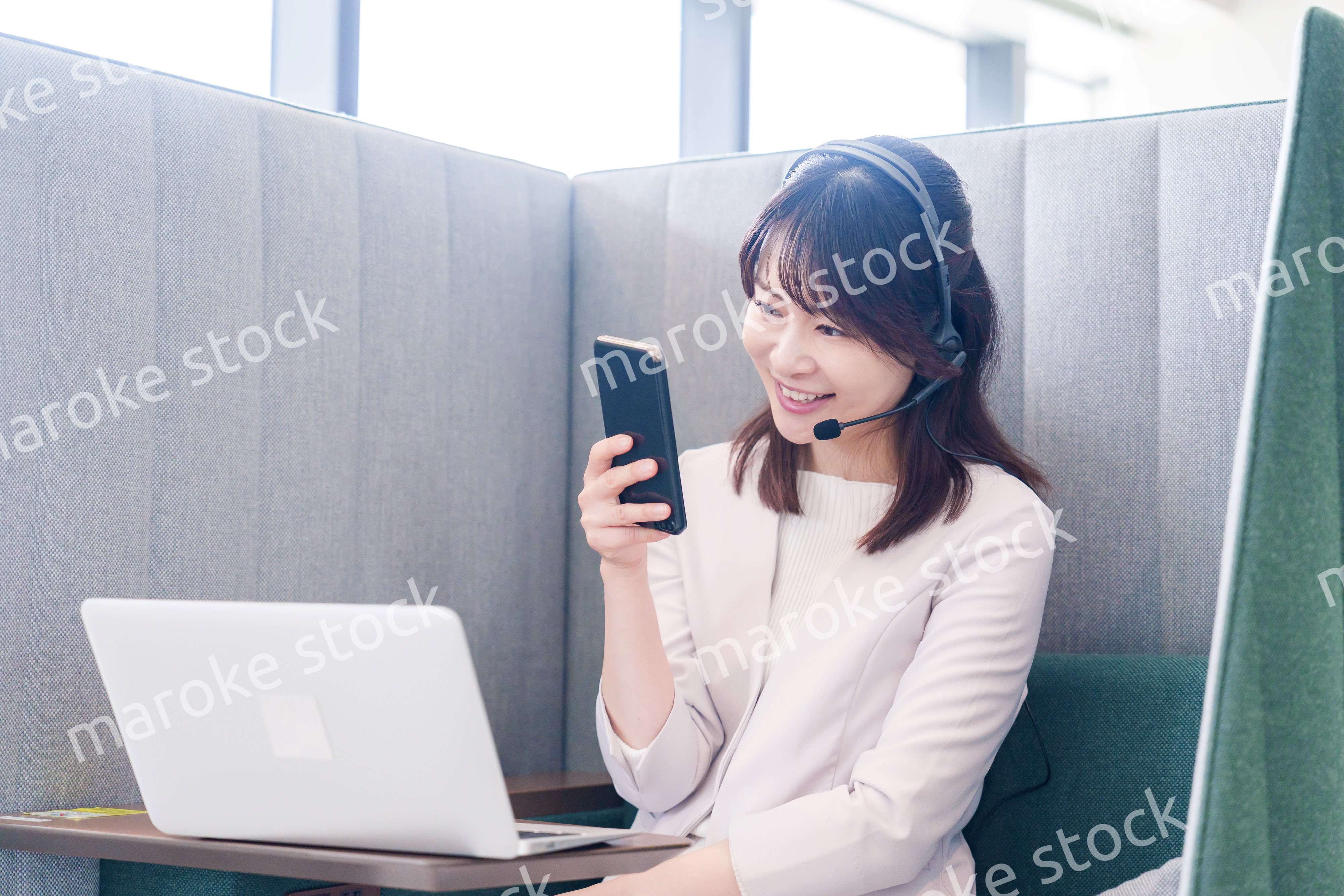 リモート会議をサボってスマホを使う若いビジネスパーソン