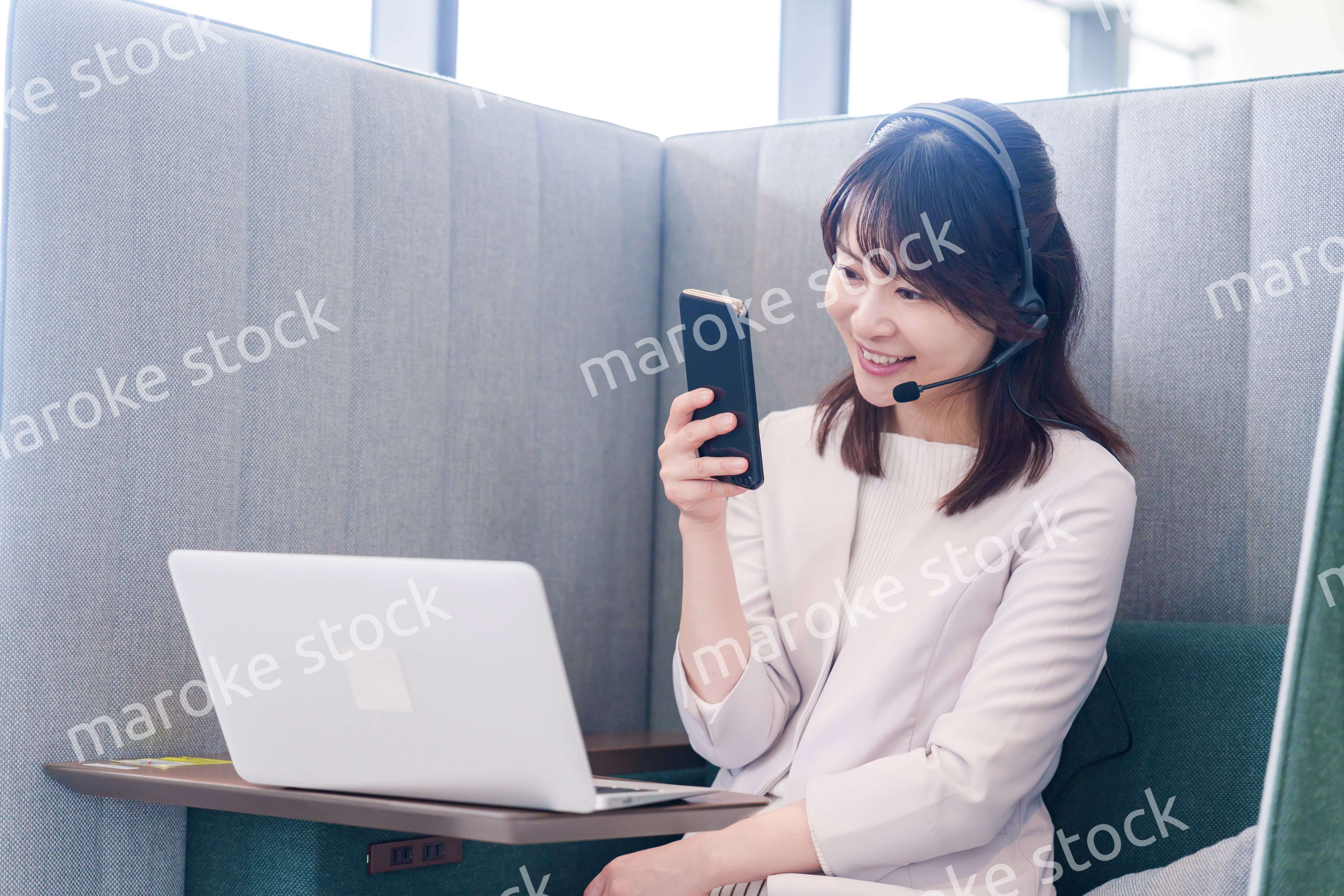 リモート会議をサボってスマホを使う若いビジネスパーソン