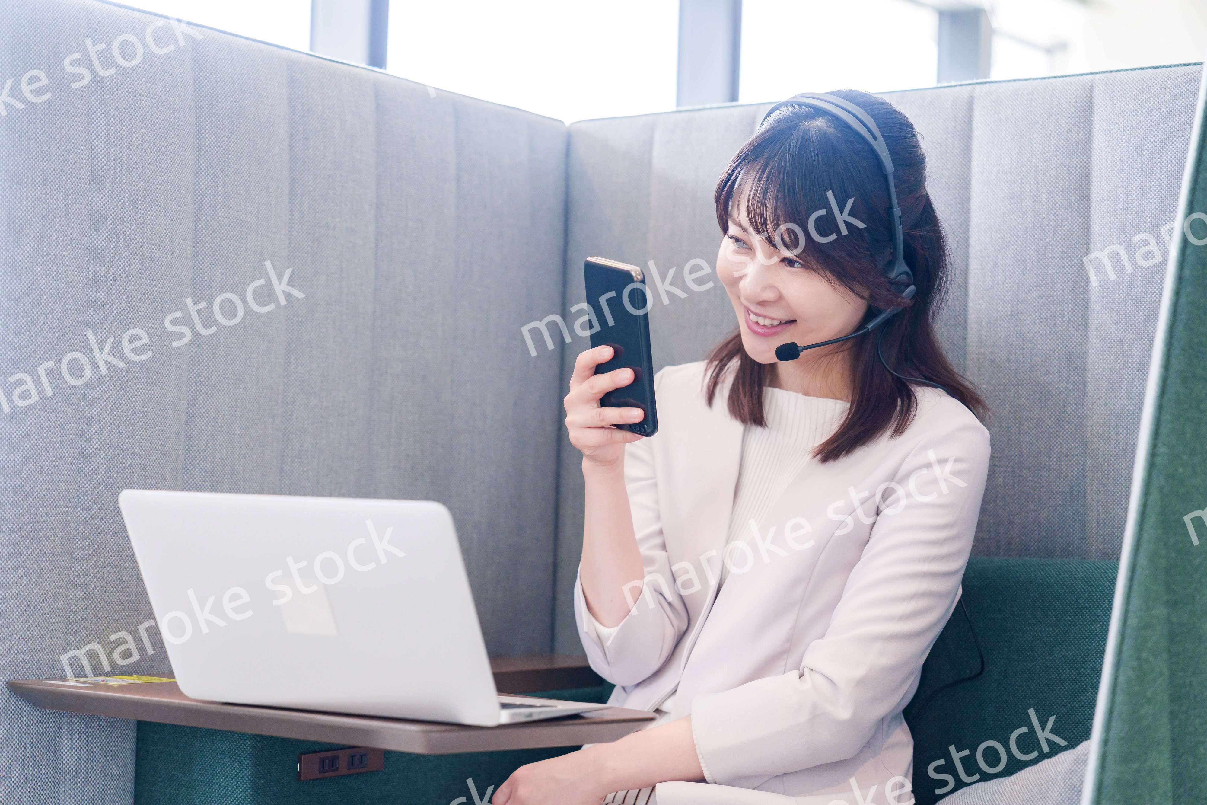 リモート会議をサボってスマホを使う若いビジネスパーソン