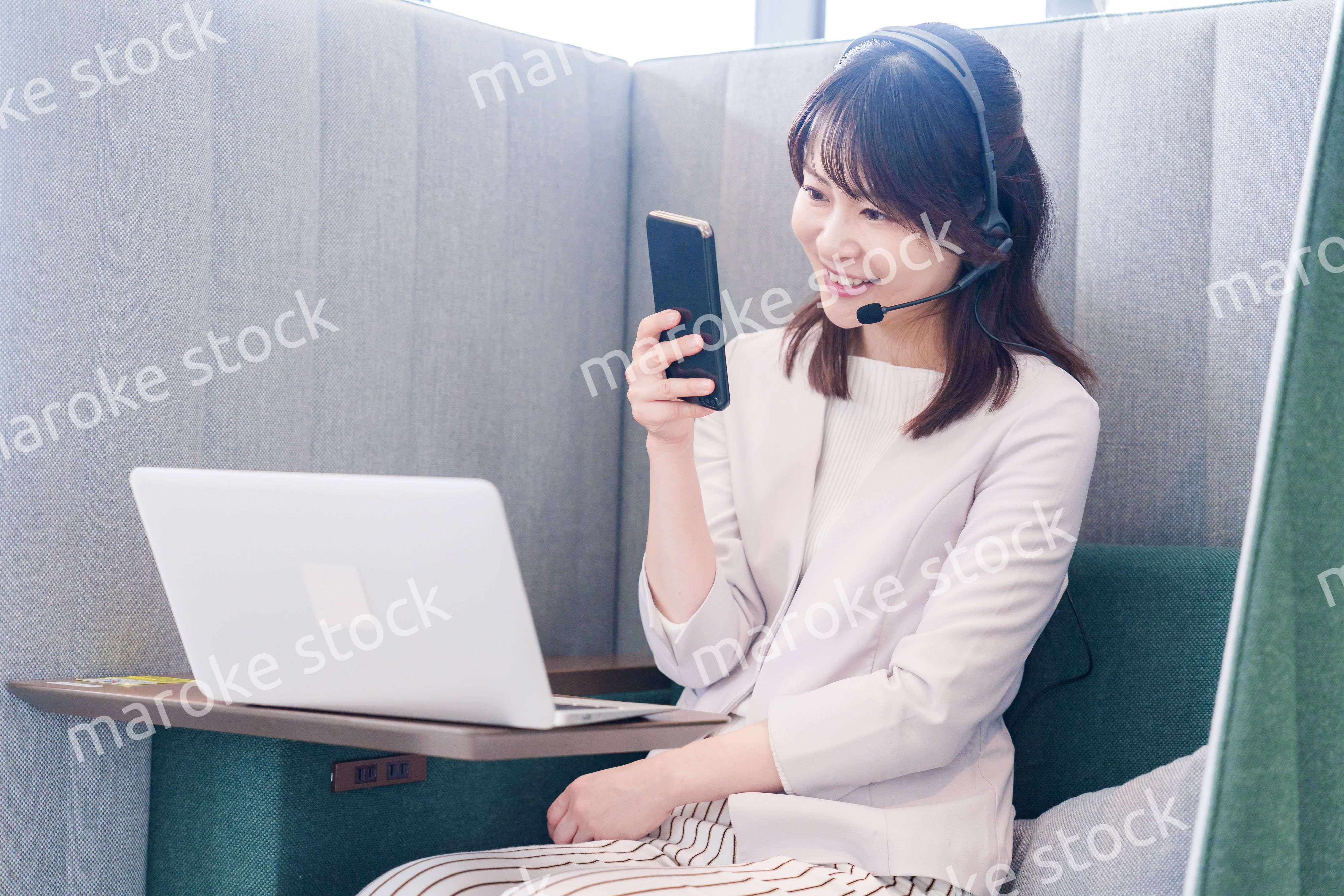 リモート会議をサボってスマホを使う若いビジネスパーソン