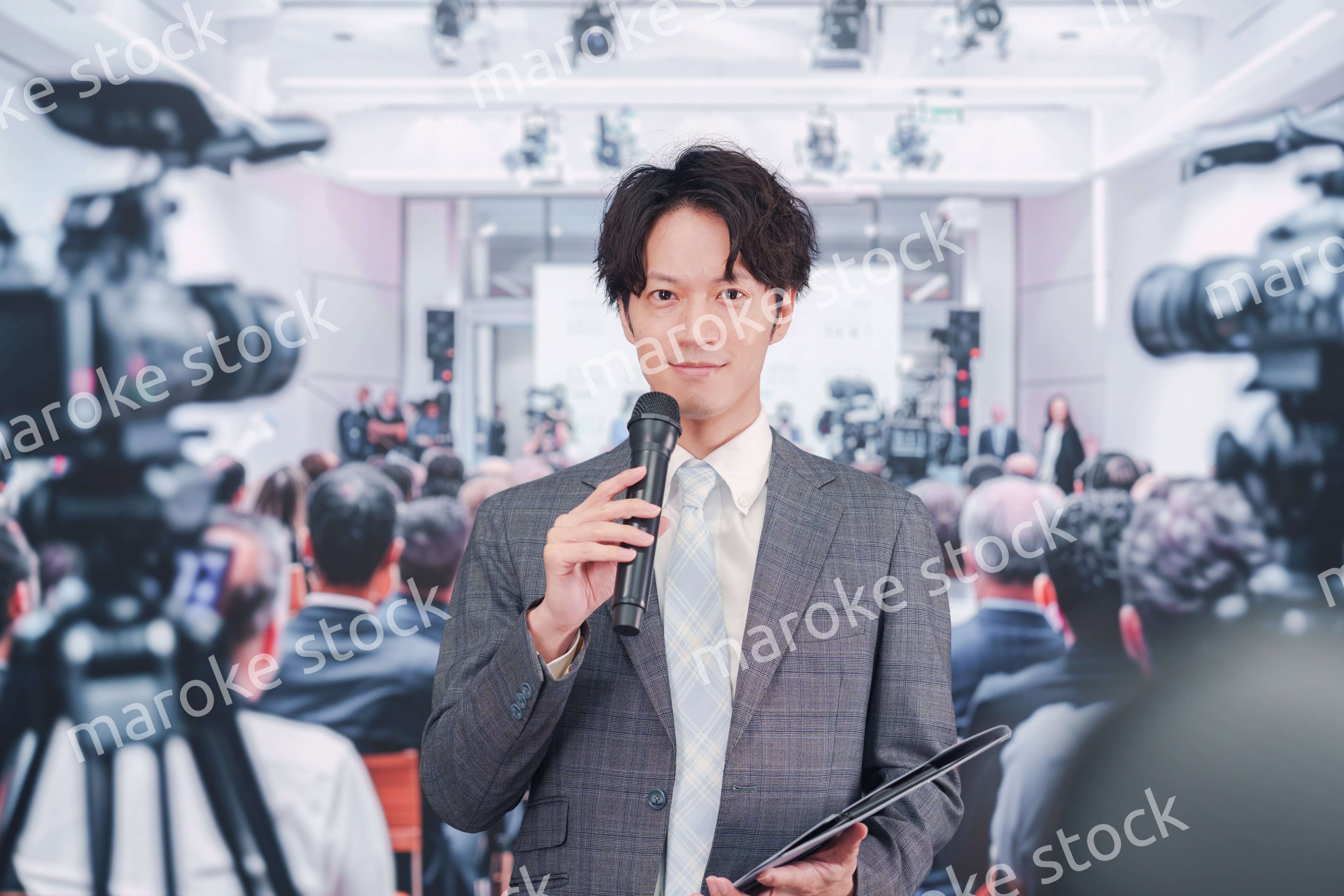 メディアが多く集まる記者会見会場で話す男性