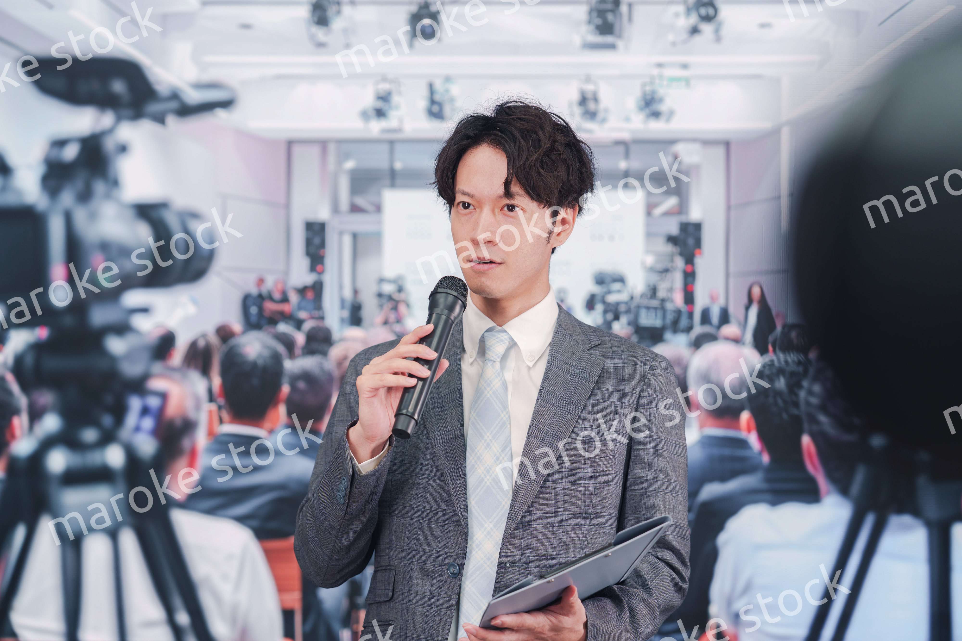 メディアが多く集まる記者会見会場で話す男性