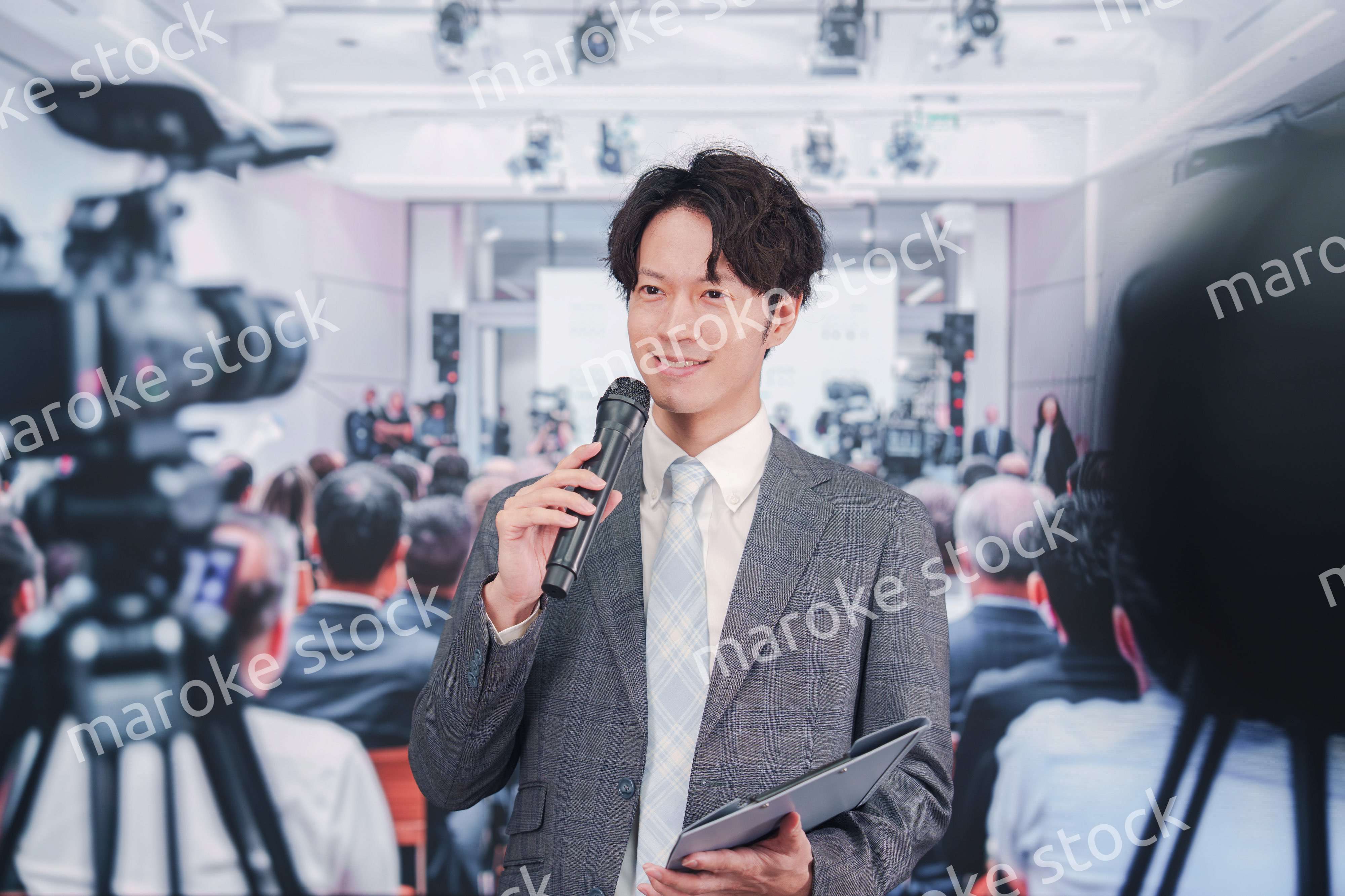 メディアが多く集まる記者会見会場で話す男性