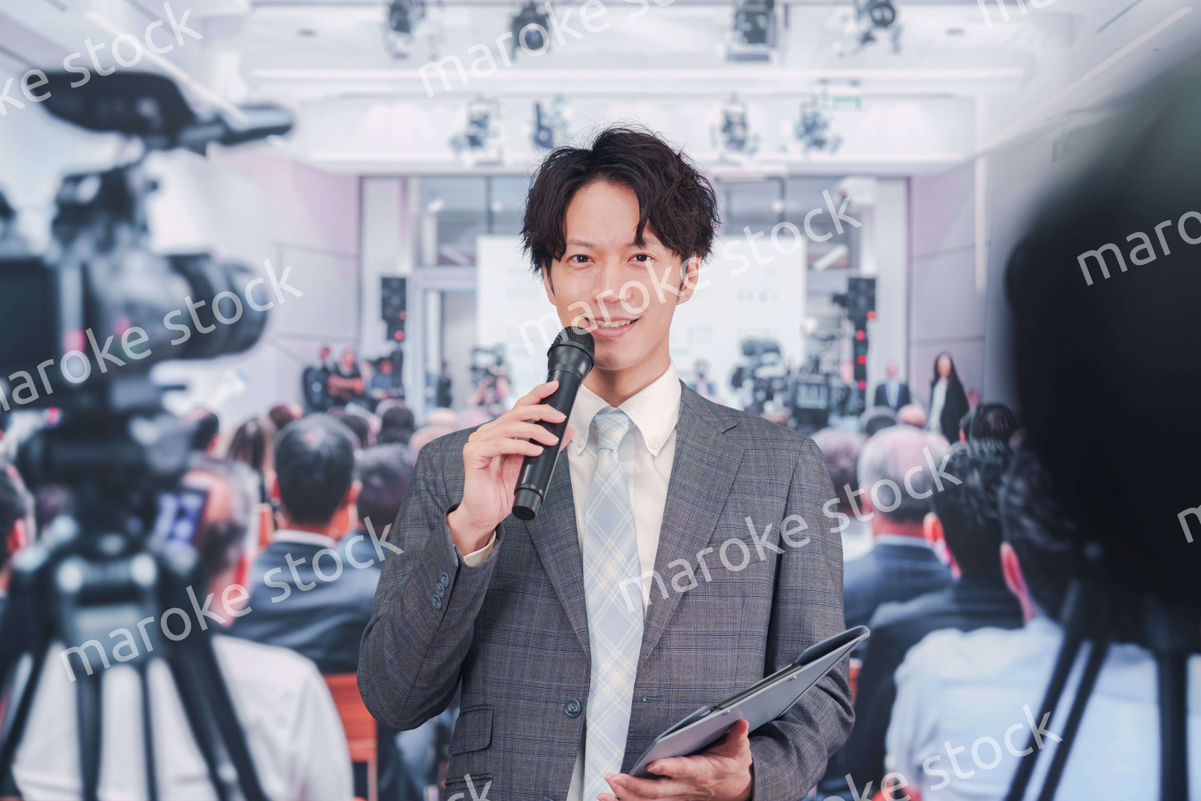 メディアが多く集まる記者会見会場で話す男性