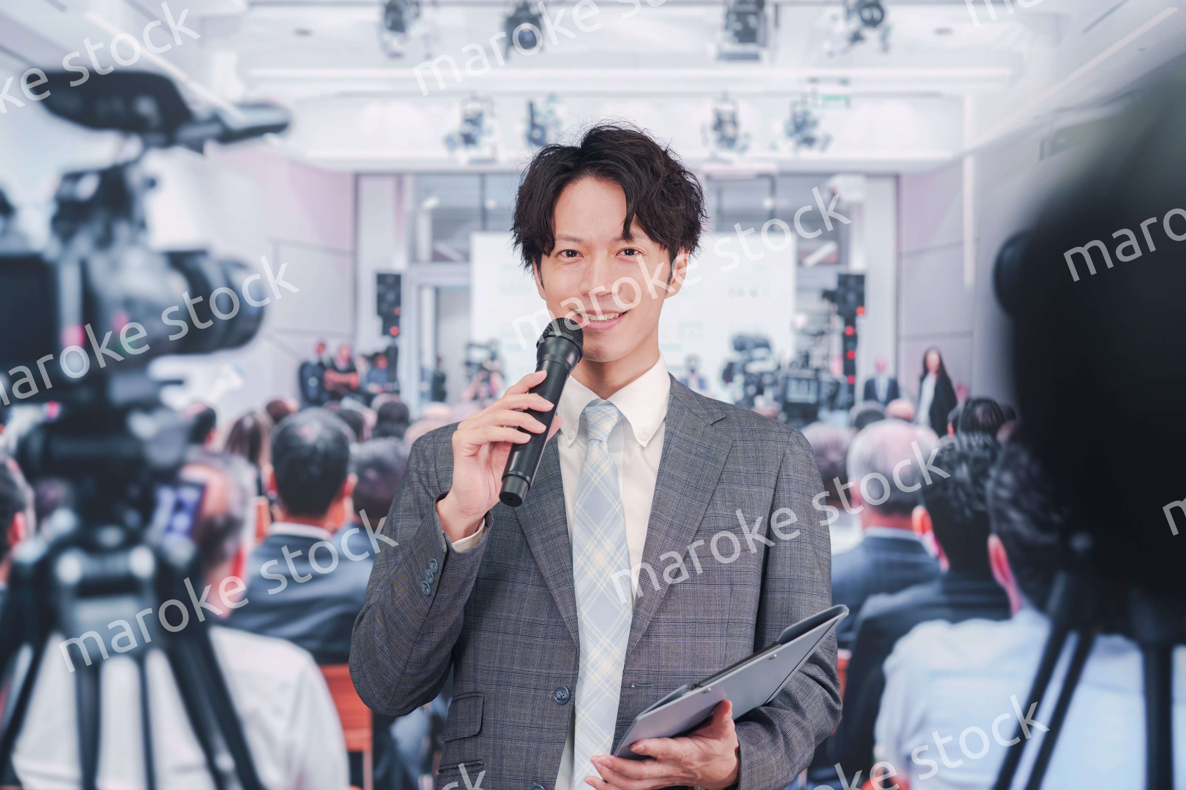 メディアが多く集まる記者会見会場で話す男性