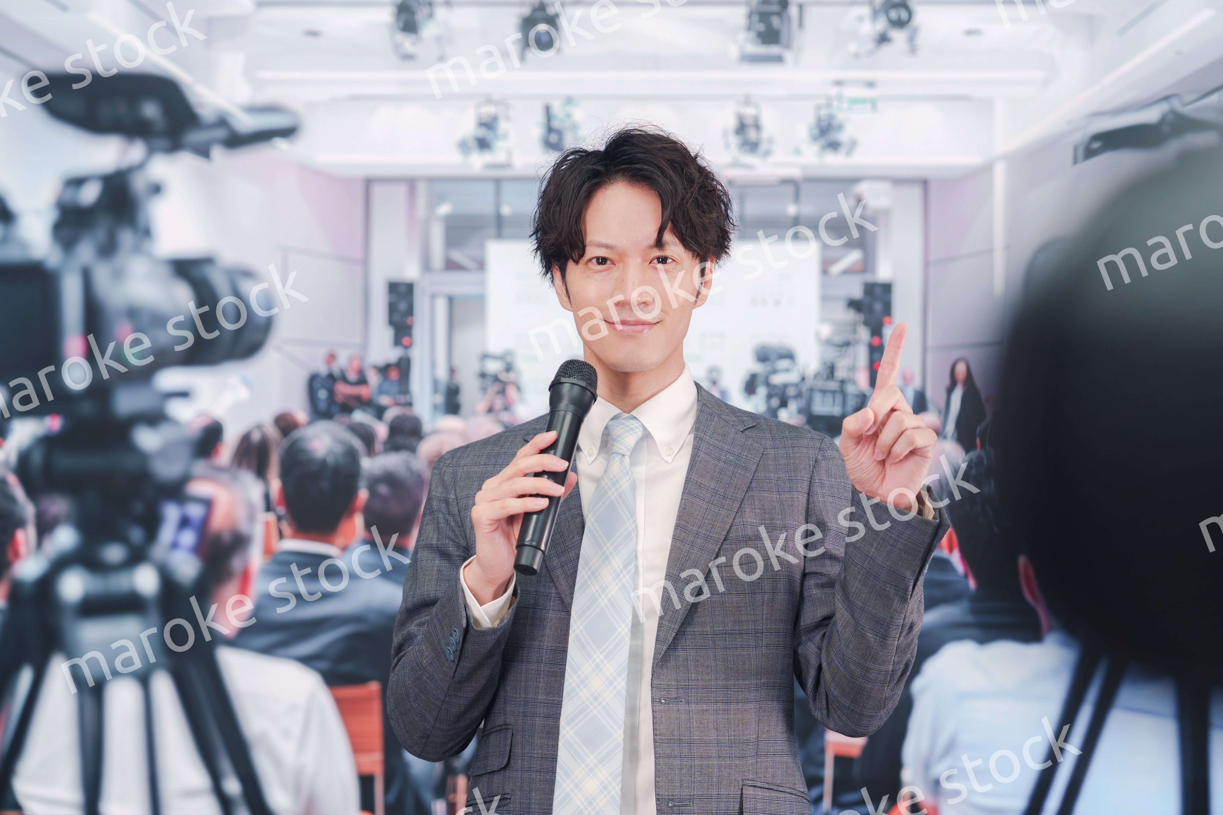 メディアが多く集まる記者会見会場で話す男性