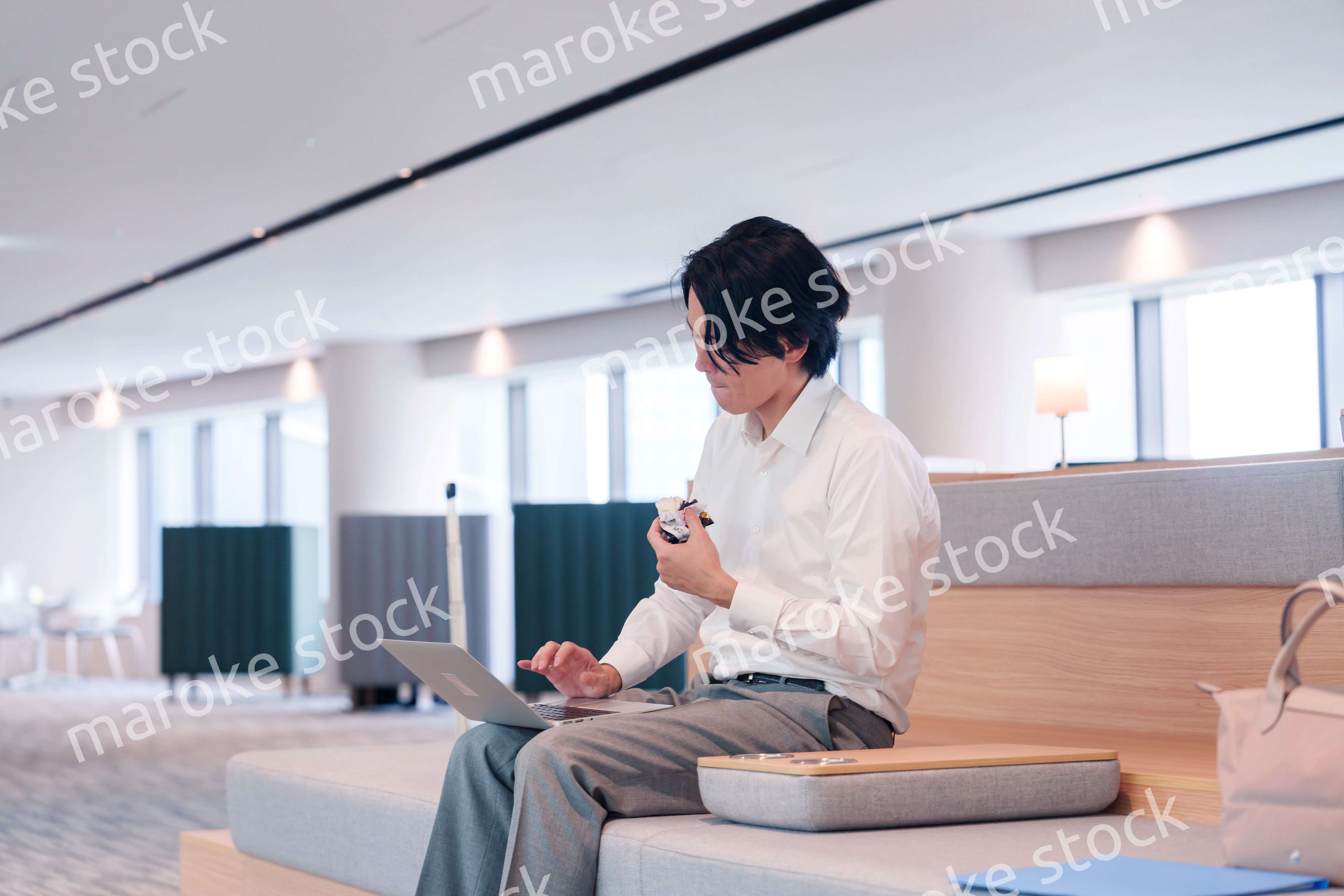 お昼ごはんを食べながらオフィスで仕事をする男性