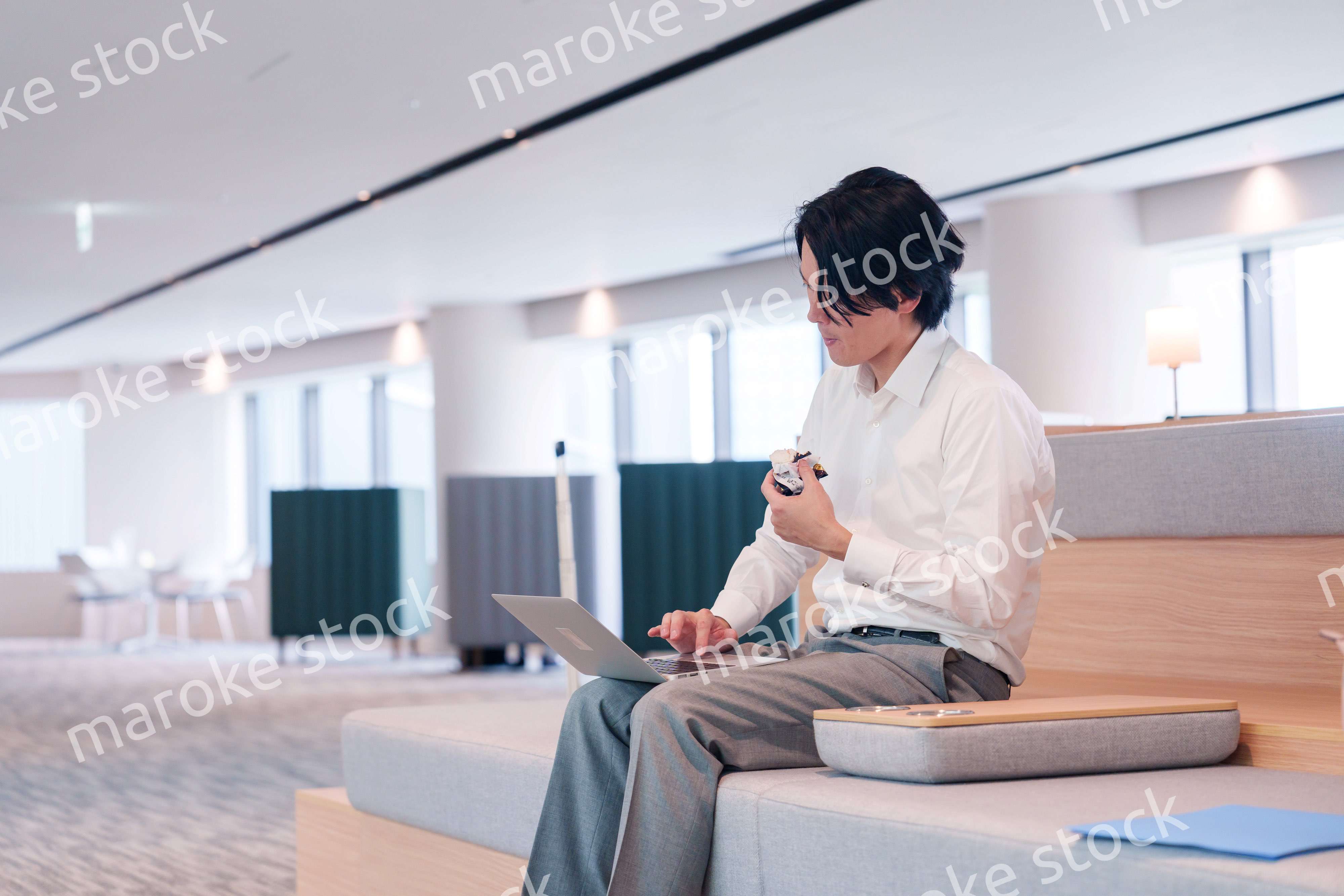 お昼ごはんを食べながらオフィスで仕事をする男性