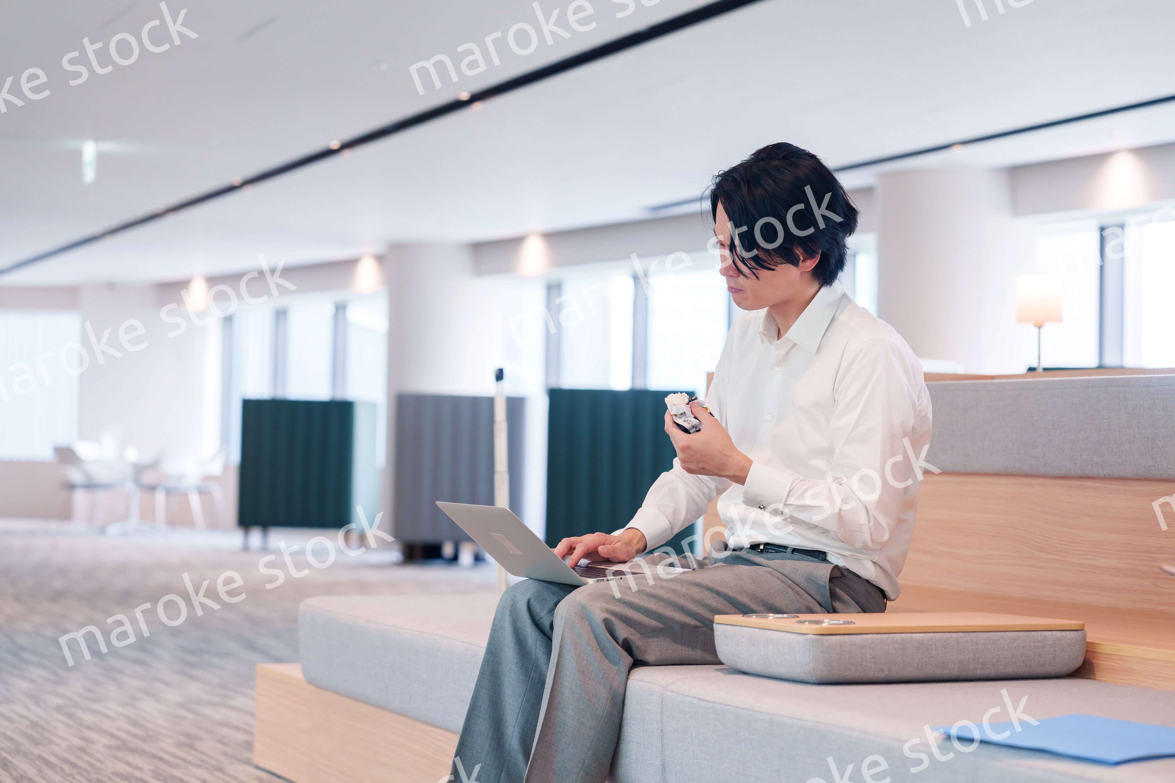 お昼ごはんを食べながらオフィスで仕事をする男性