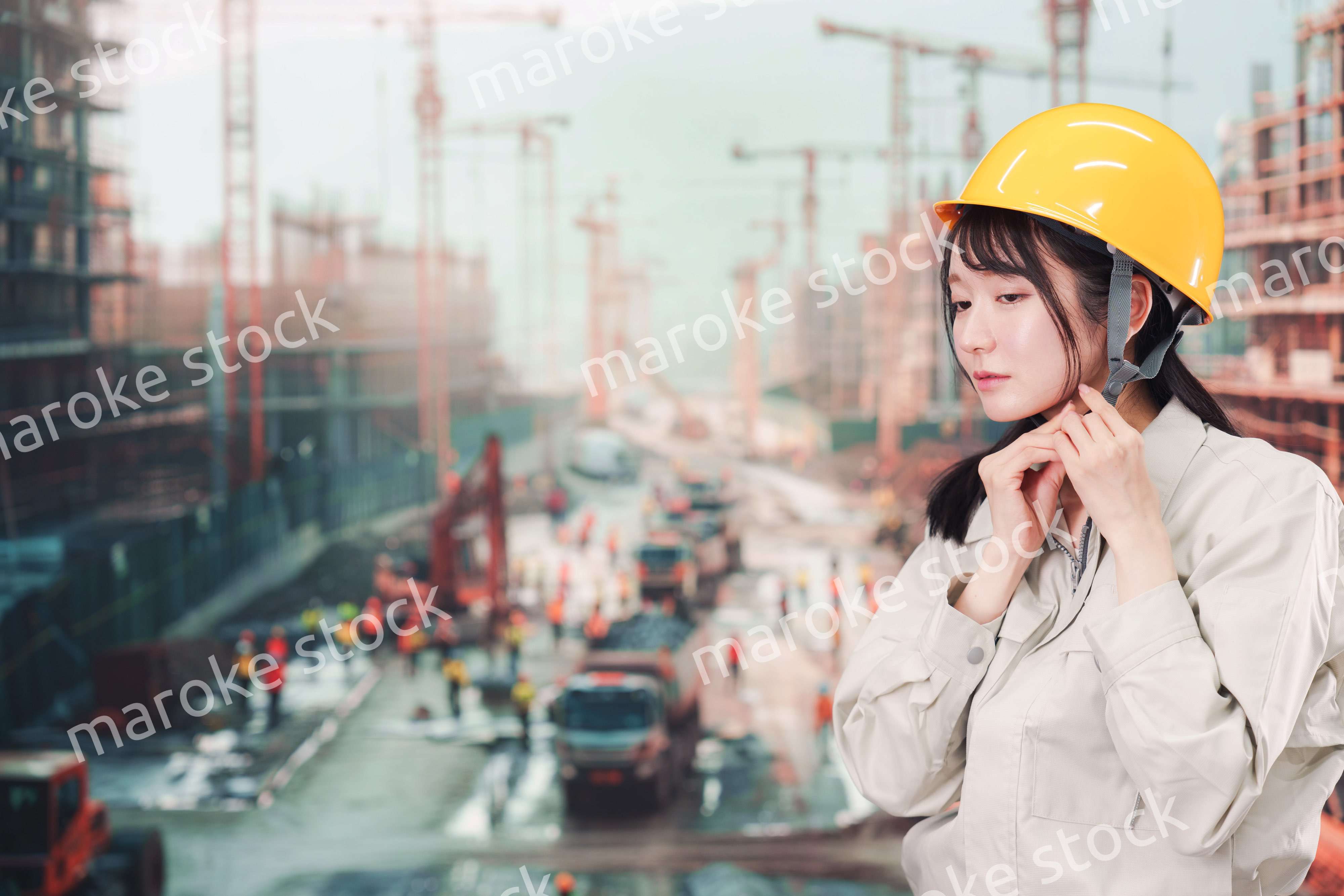 建設現場でヘルメットを装着する作業服姿の女性